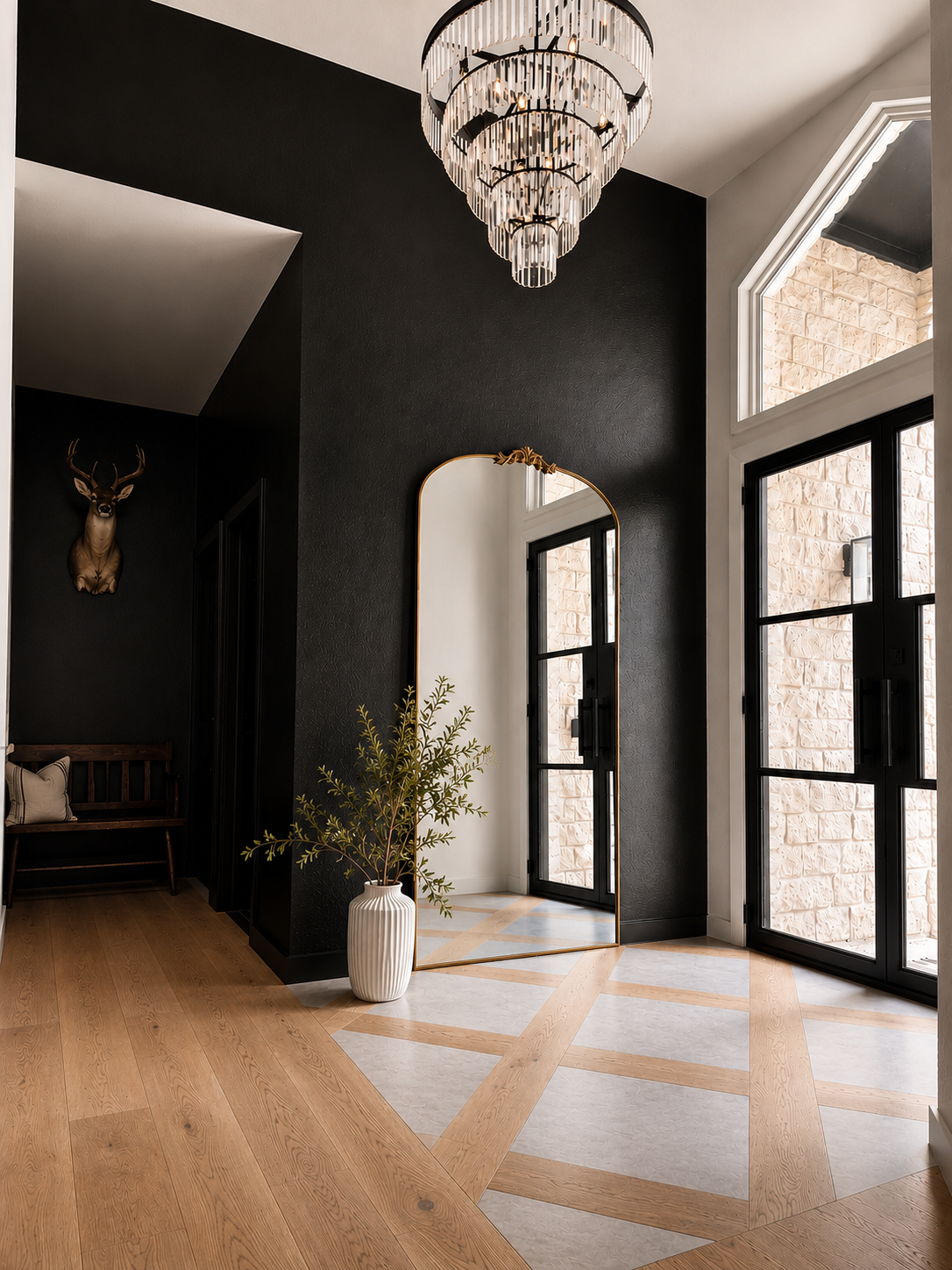 Custom entryway renovation in Old Lakeway featuring intricate patterned flooring, a black accent wall, grand chandelier, and modern steel front door