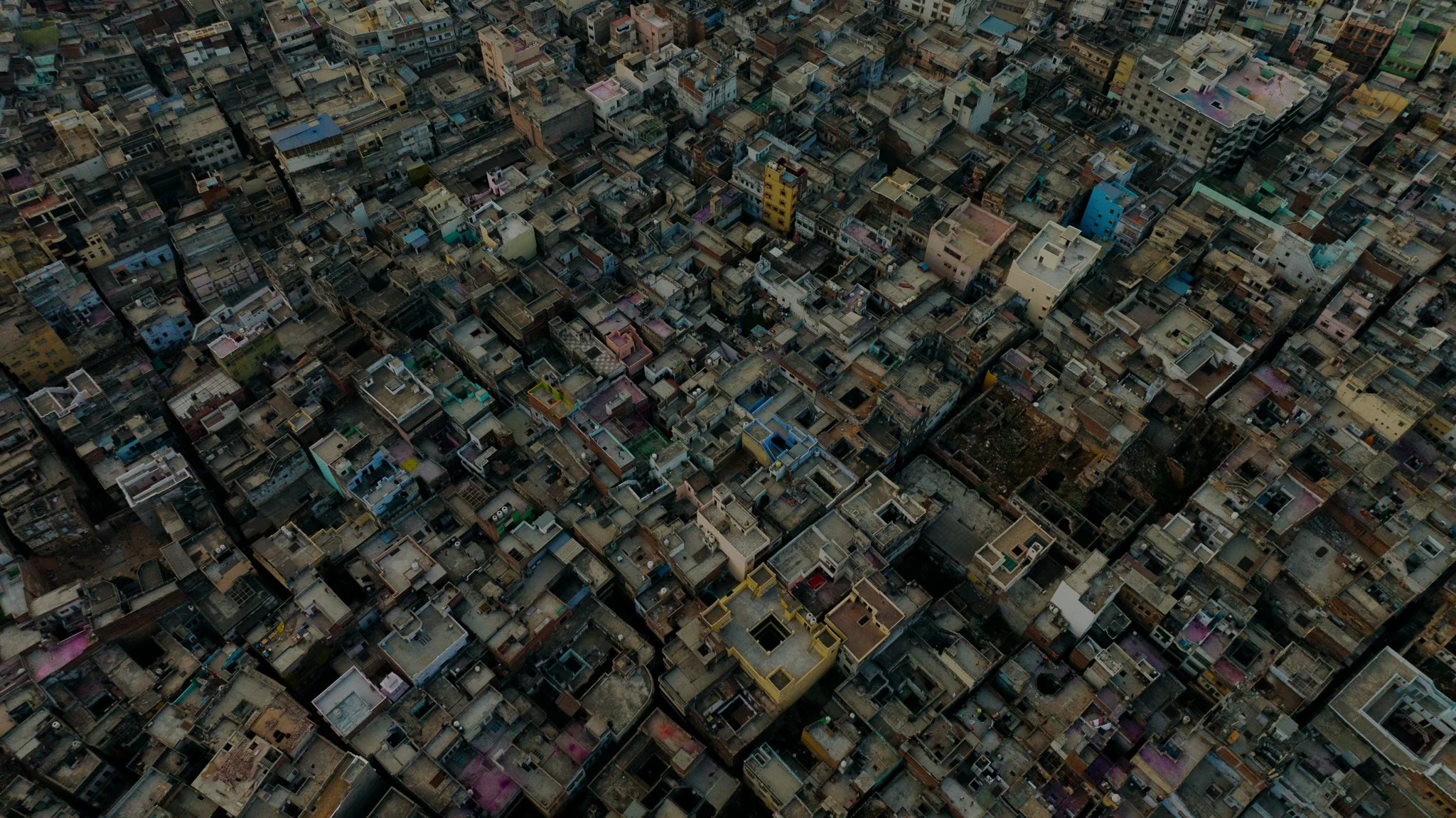 Aerial view of densely packed buildings in a city with narrow streets and rooftops of various colors and heights.