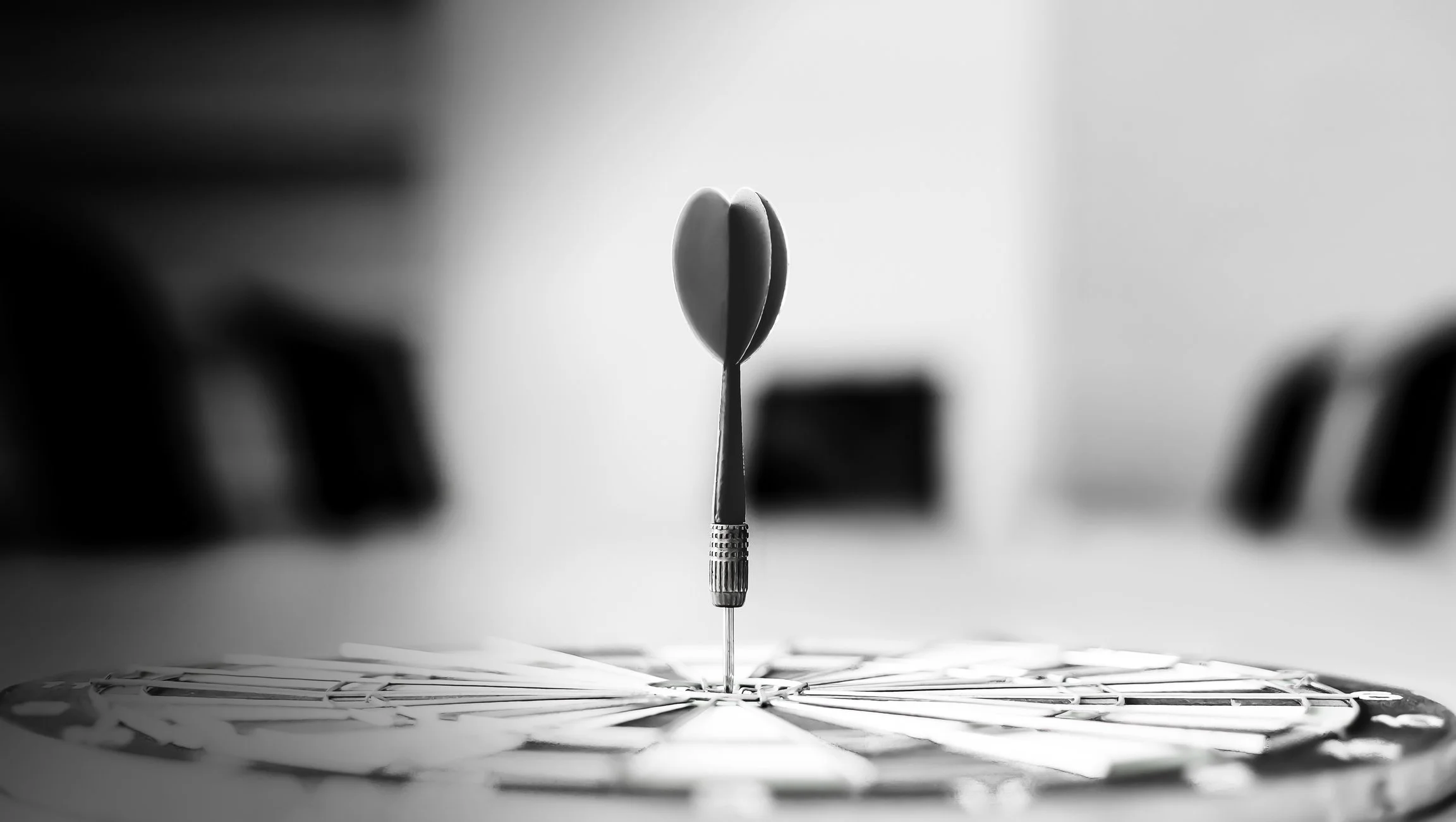 A dart hitting the center of a dartboard with a dart embedded in the bullseye.