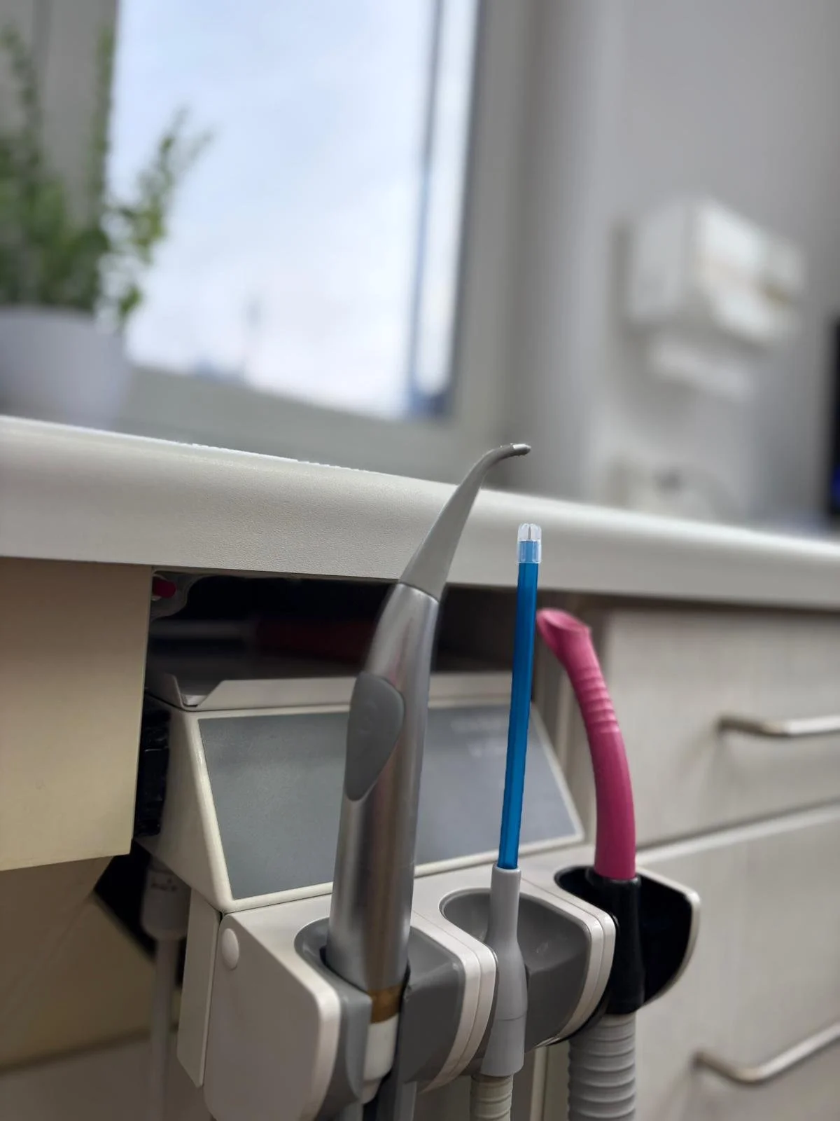 Zahnarztinstrumente im Badezimmer in einer Ablage, mit einem Fenster im Hintergrund.