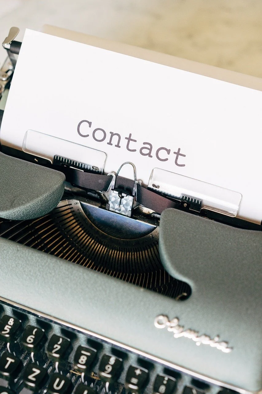 A contact page printed on a sheet of paper inserted into a vintage typewriter.
