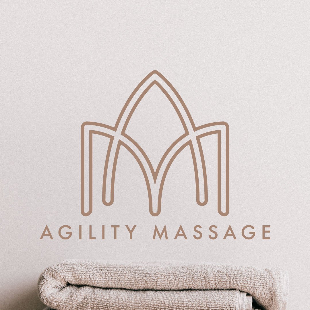 A logo with a stylized leaf or petal design above the words 'Agility Massage' on a white wall, with a folded towel in front.