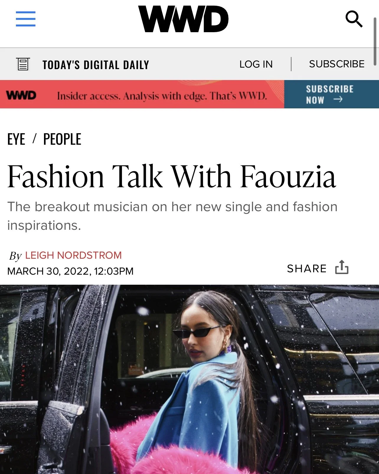 A woman wearing sunglasses and a blue jacket sitting in a car with a pink fuzzy blanket, with raindrops on the car window and a reflection of streetlights.