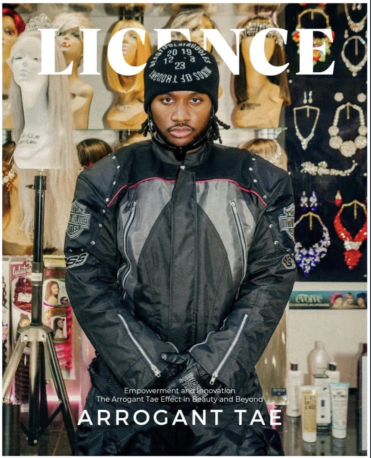 Cover of a magazine titled "License" featuring a man in motorcycle gear standing with arms crossed in front of a display of wigs and jewelry, with the text "Empowerment and innovation: The Arrogant Tae Effect in Beauty and Beyond," and the name "Arro