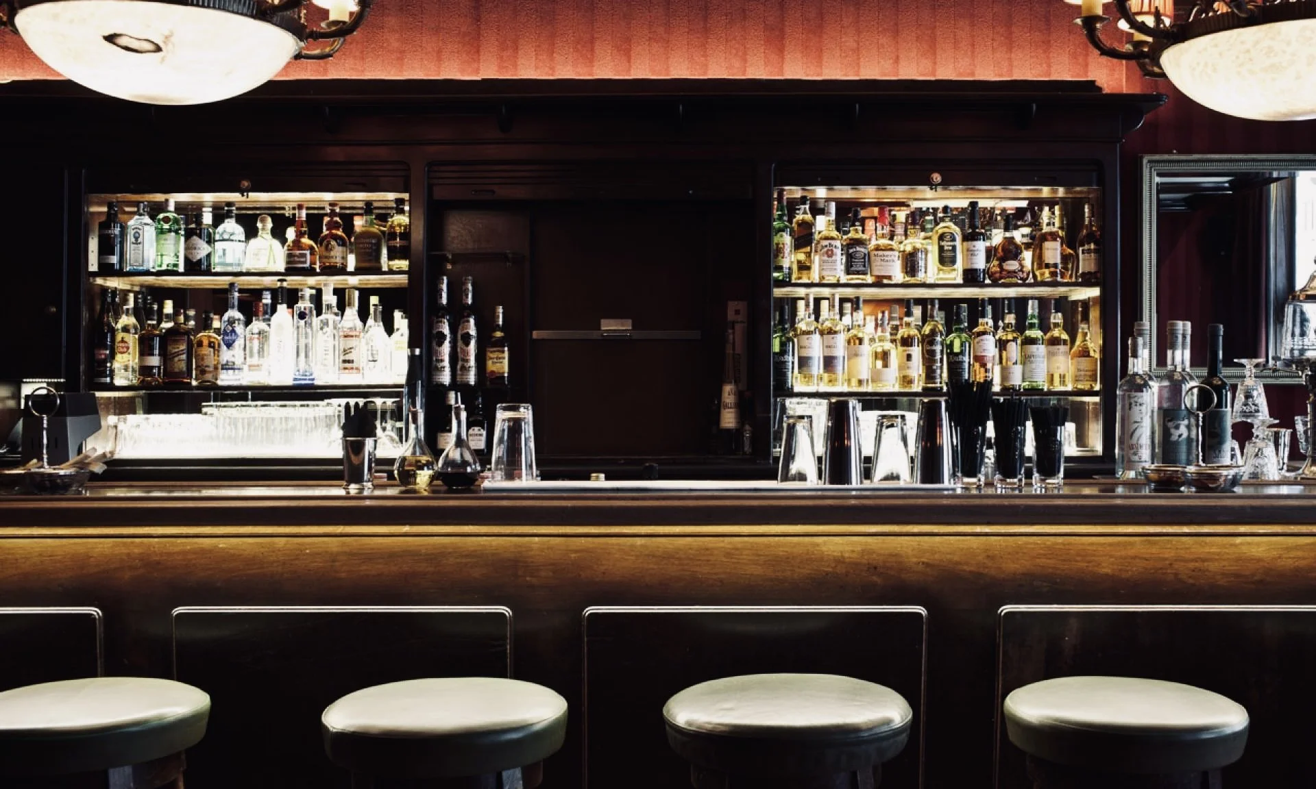 Brennbarregal hinter einer Bar mit verschiedenen Spirituosen und Gläsern.