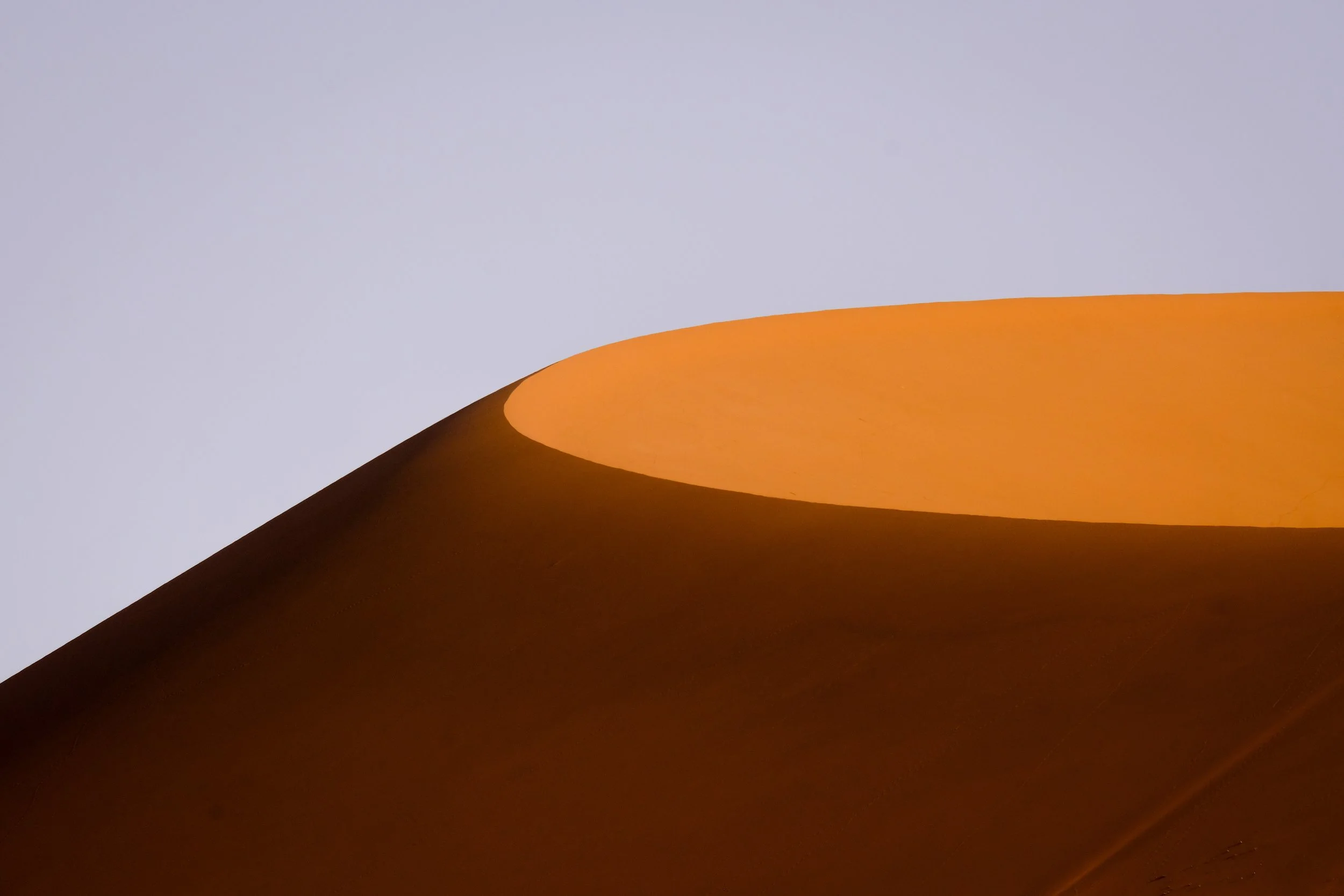Orange sand dune with a flat ridge under a clear sky, used to represent Cognitive Behavioral Therapy (CBT).