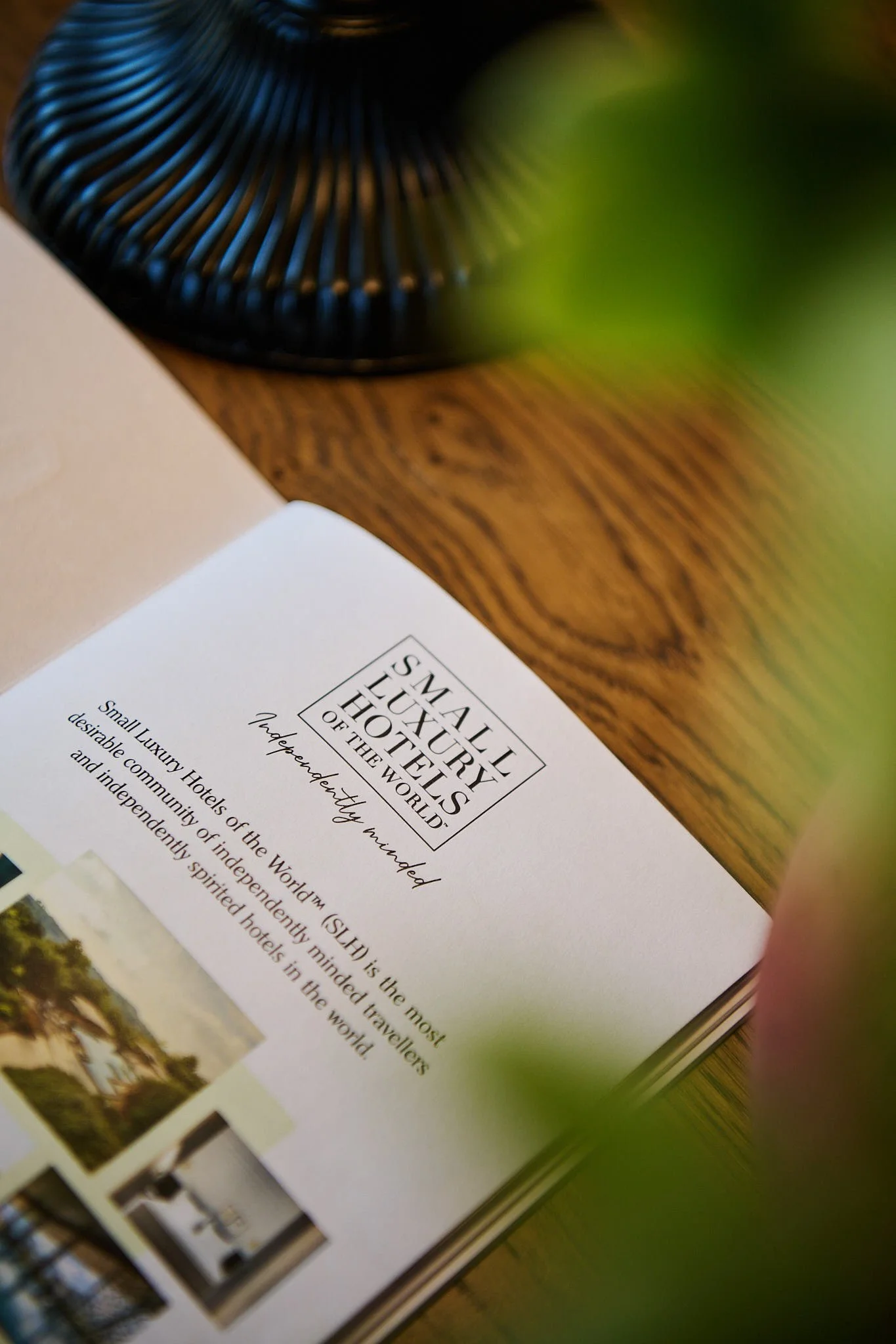 Close-up of a brochure or pamphlet titled 'Small Luxury Hotels of the World' with the tagline 'Independently minded'. The page contains text describing the hotels and includes small photographs of hotel exteriors and interiors. The scene is set on a 