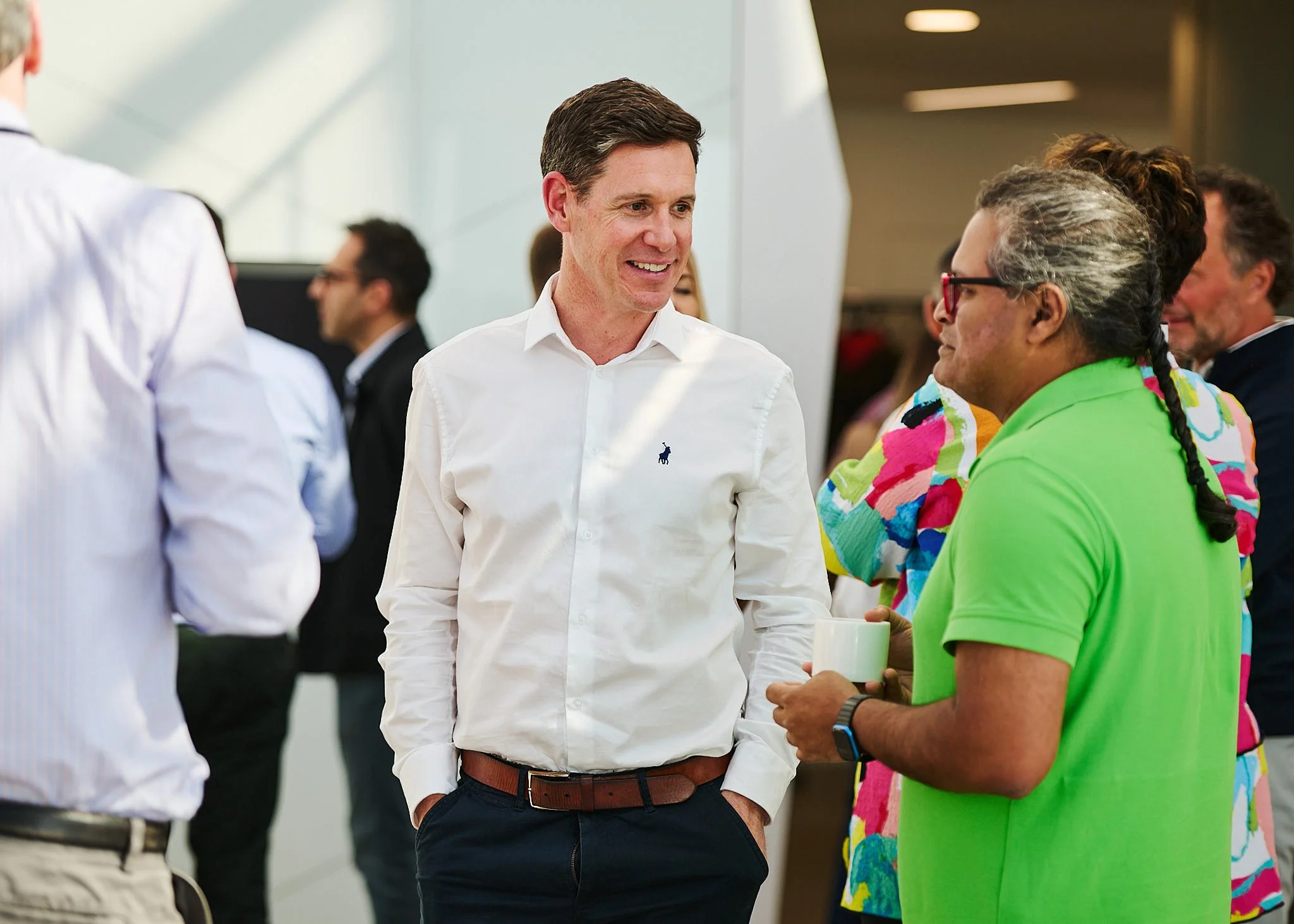 People engaged in a conversation at a professional or social event in a brightly lit indoor space.