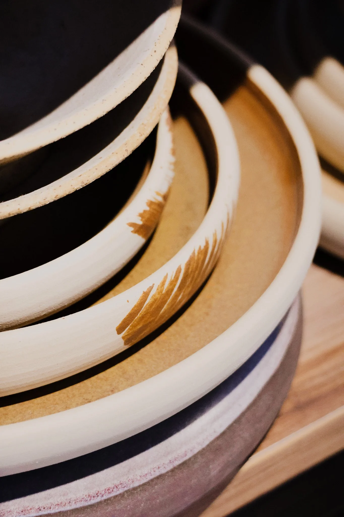 Stacked ceramic bowls in neutral colors, including black, beige, and white, on a wooden surface.