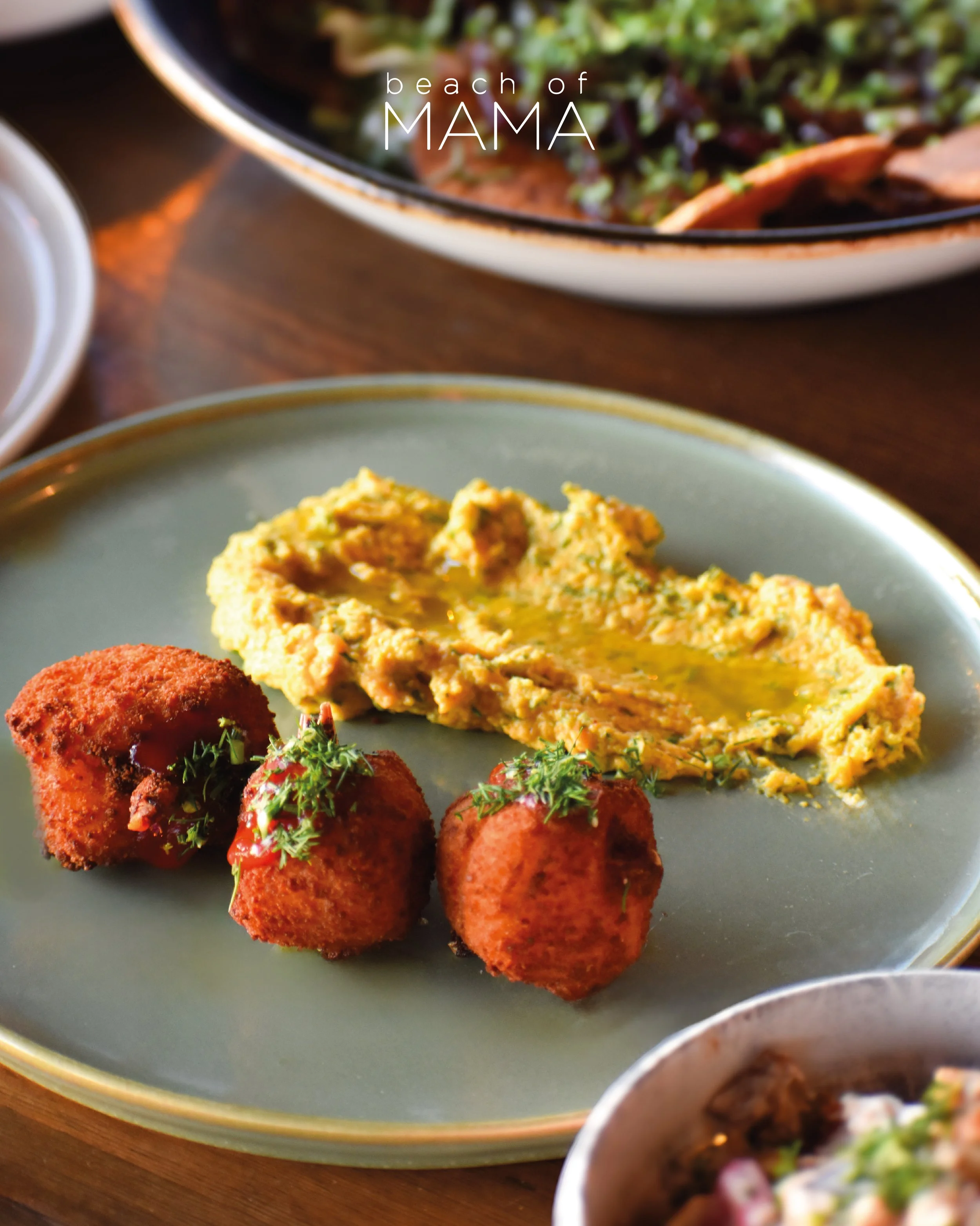 Plate with three fried croquettes garnished with herbs and three spoonfuls of yellowish guacamole on a light green dish.