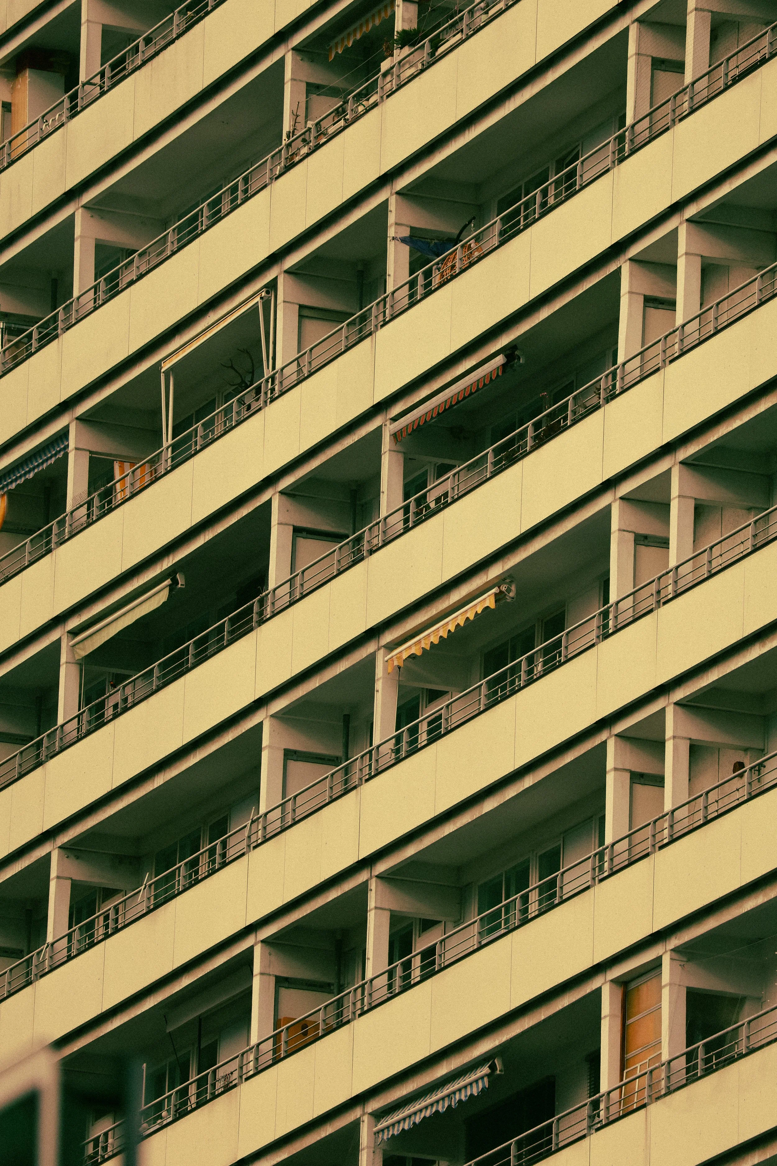 Close-up of a multistory apartment building with balconies, some with curtains or awnings, and a few with laundry or outdoor furniture.