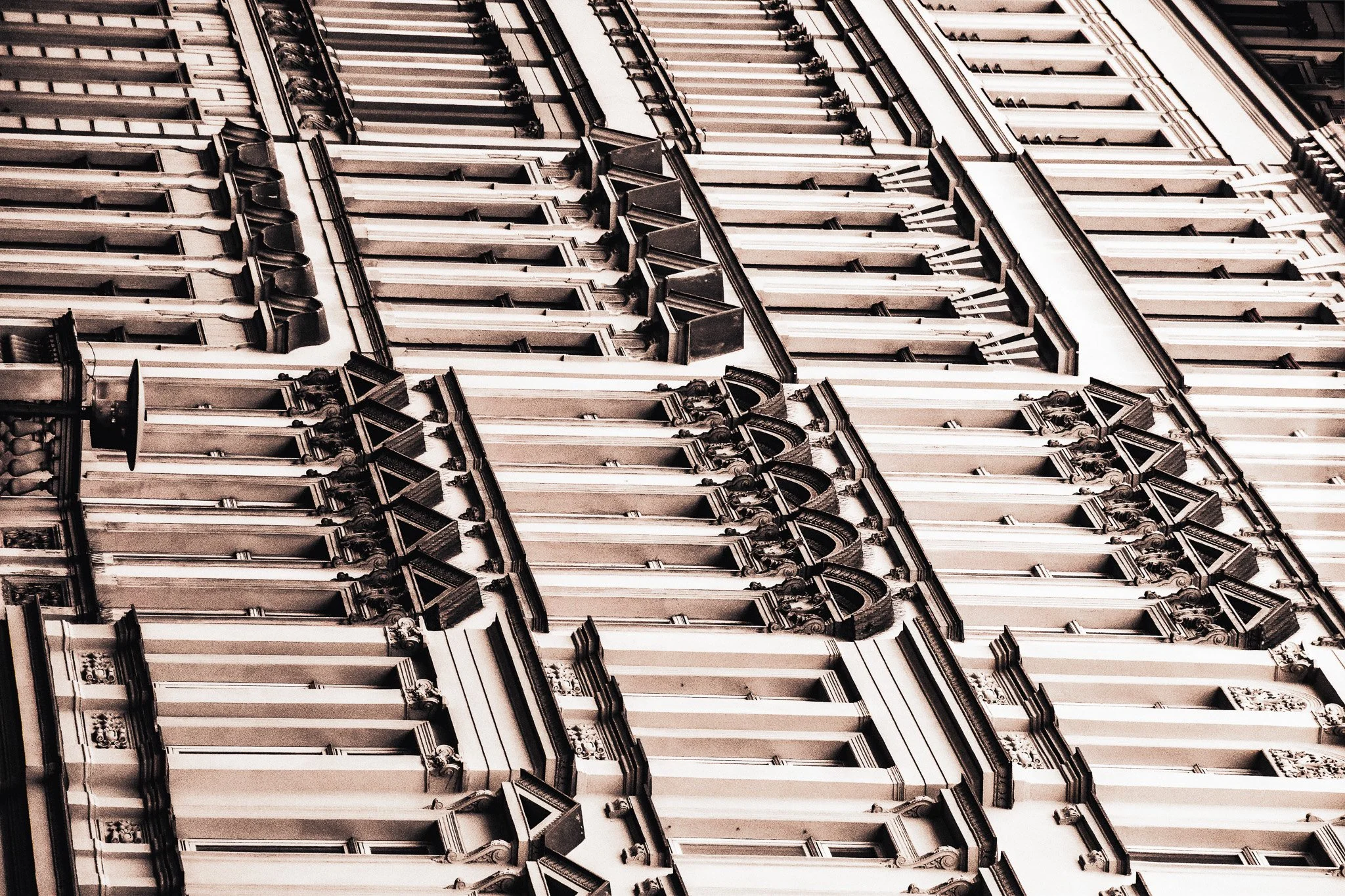 Close-up of an ornate, historic building facade with multiple rows of windows and detailed architectural decorations in a vintage style.