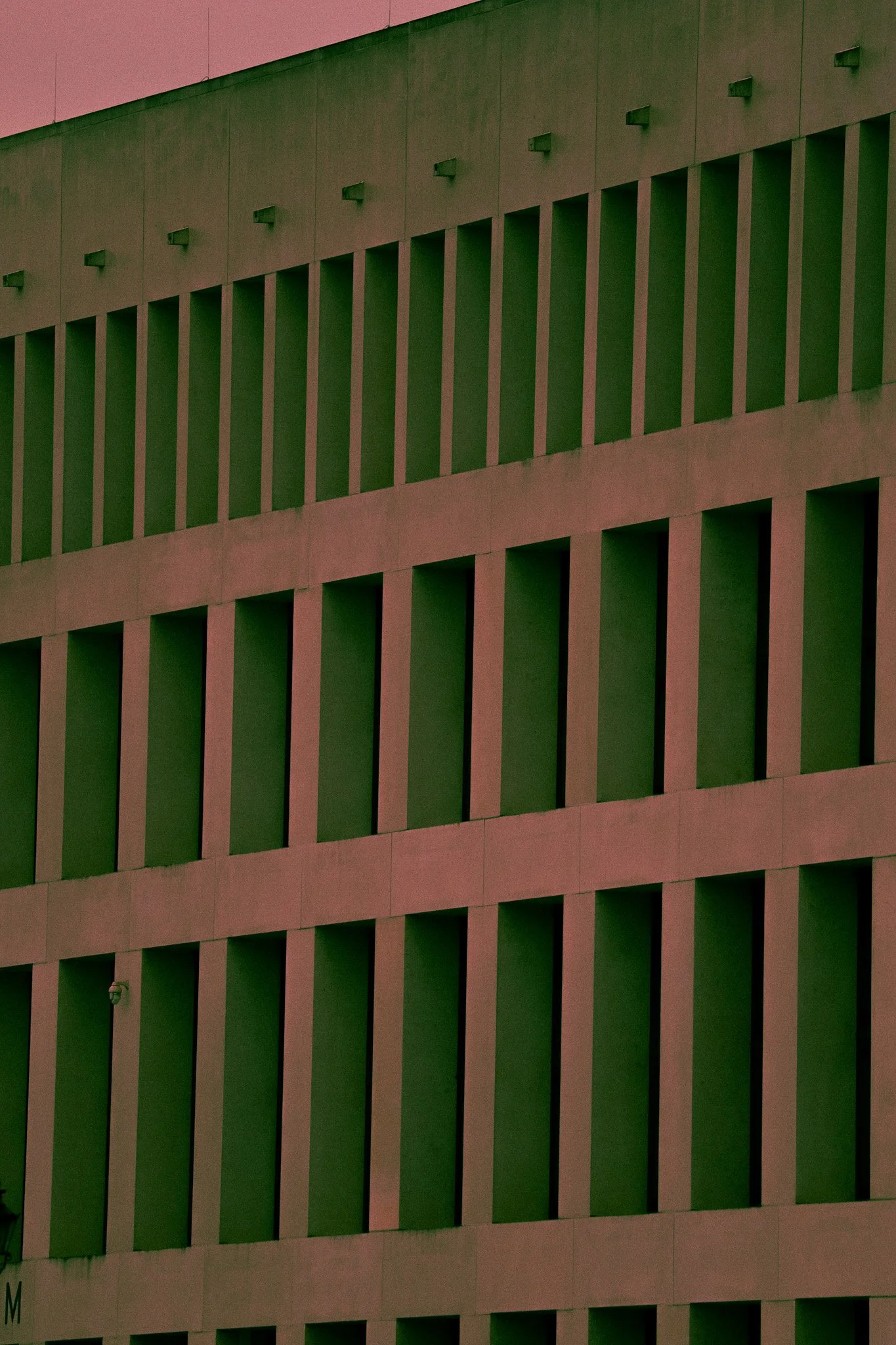 Close-up of a modern building's facade with alternating green and beige vertical and horizontal sections.