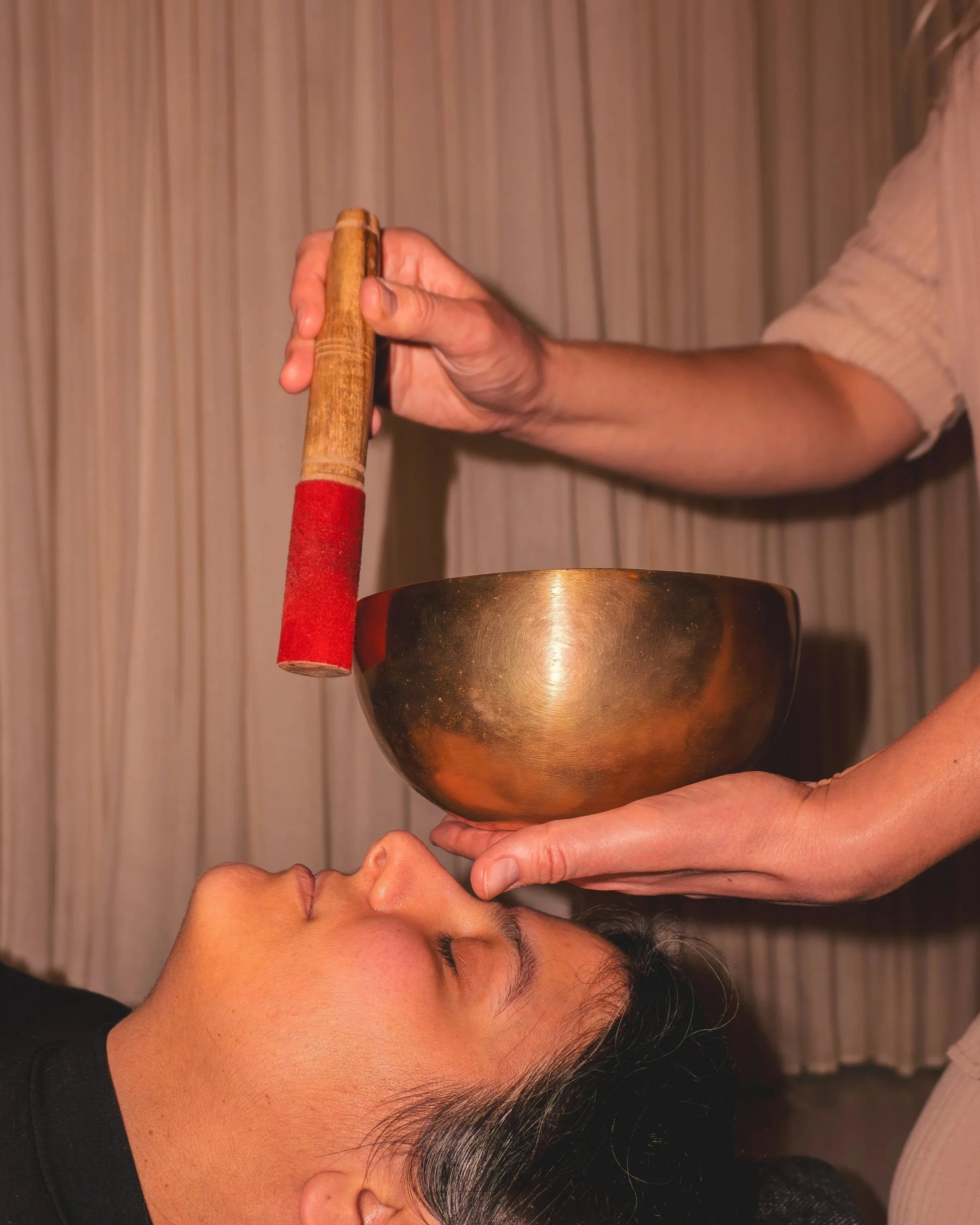 Person receiving sound therapy with a himalayan singing bowl during session.