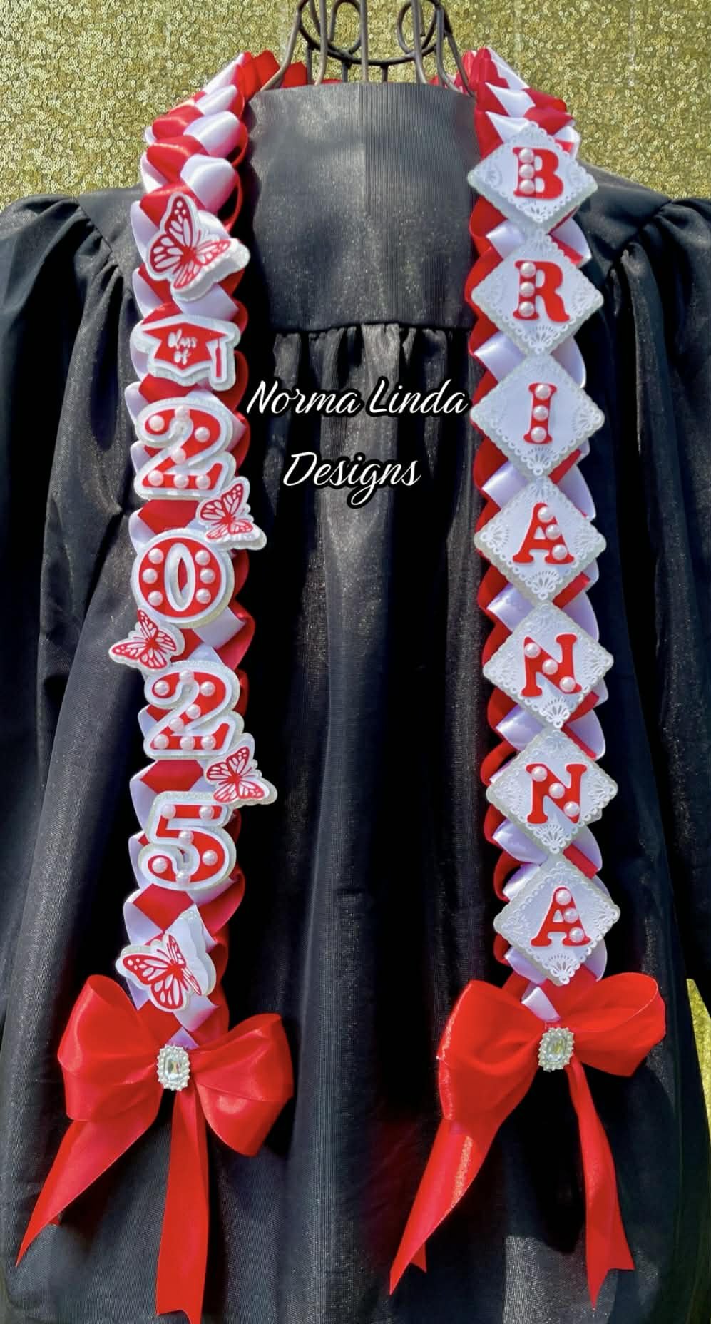 Front facing view of graduation lei in red and white. Featuring Brianna and 2025 letters and butterfly accents. Red bows on the bottom with gemstones.
