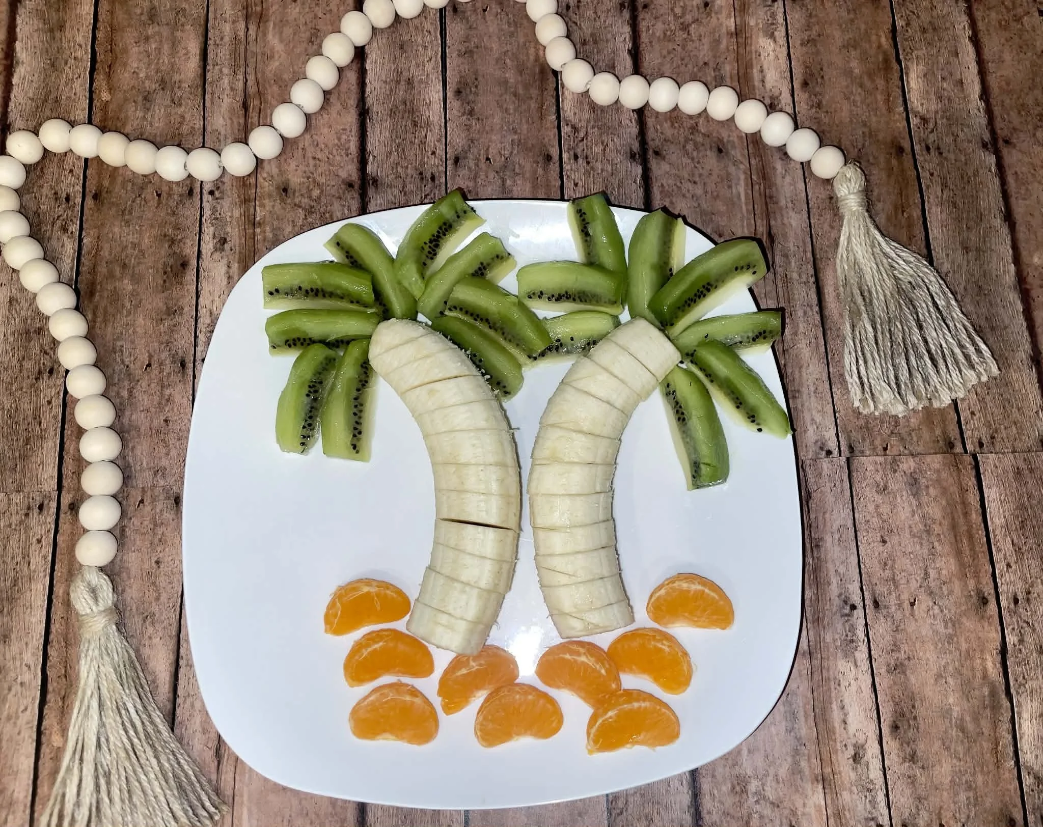 Banana, orange and kiwi cut and stacked to form palm tree design