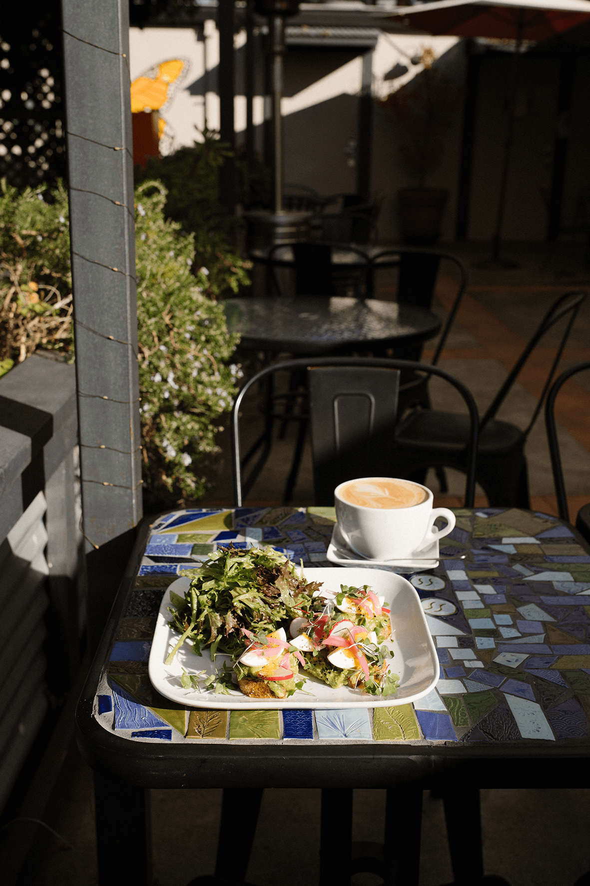 A table with a salad and a cup of coffee at an outdoor cafe.
