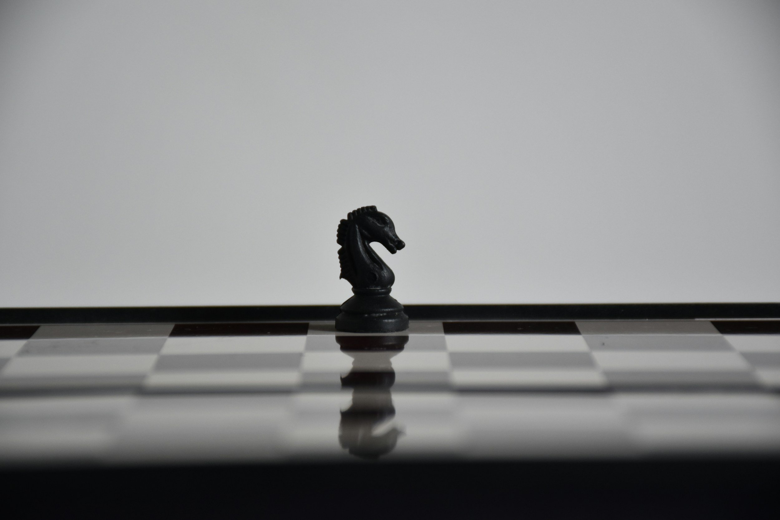 A chessboard with a single knight standing alone, isolated from other pieces.