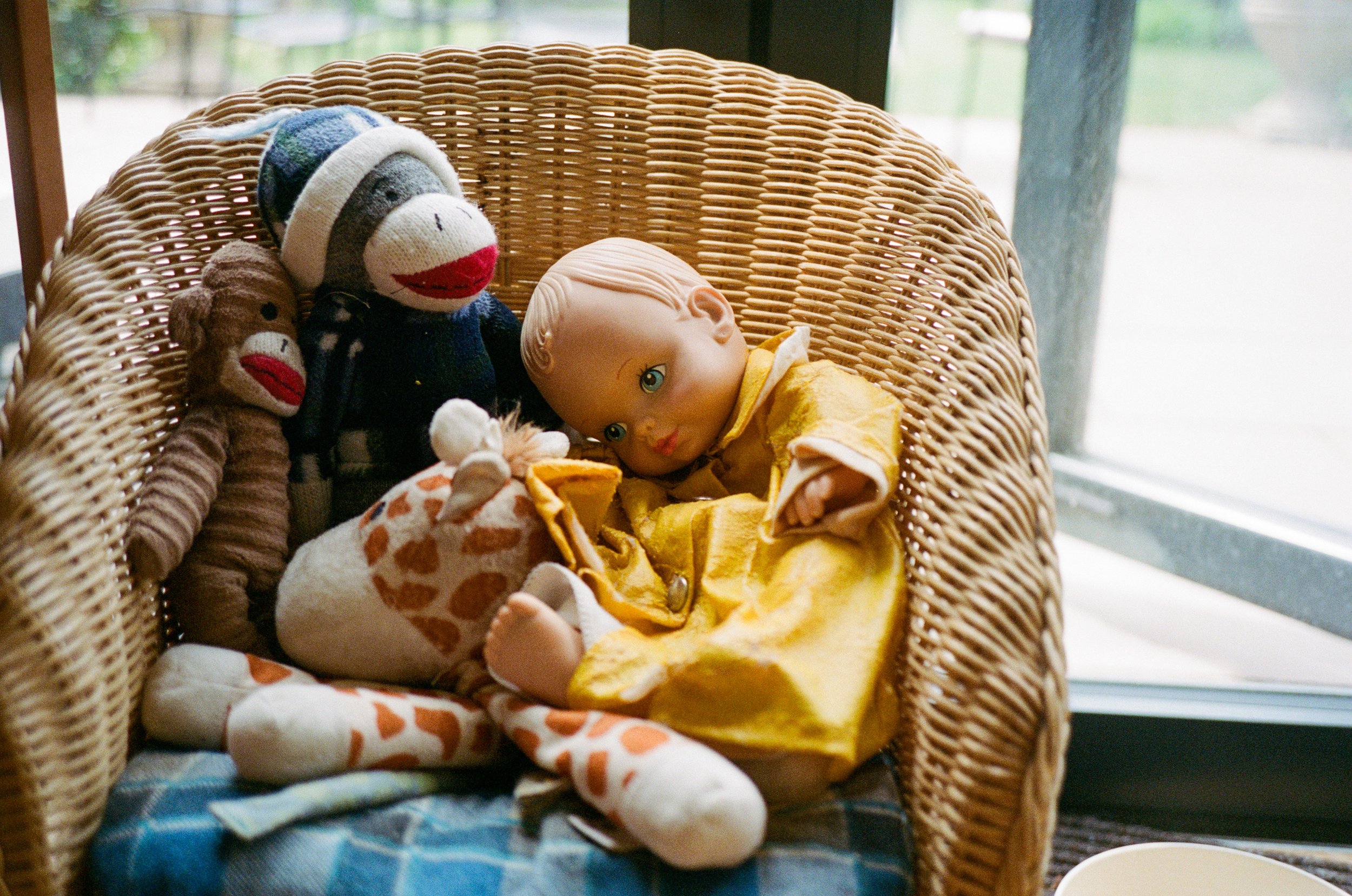 Children’s toys neatly arranged in wicker chair by window.