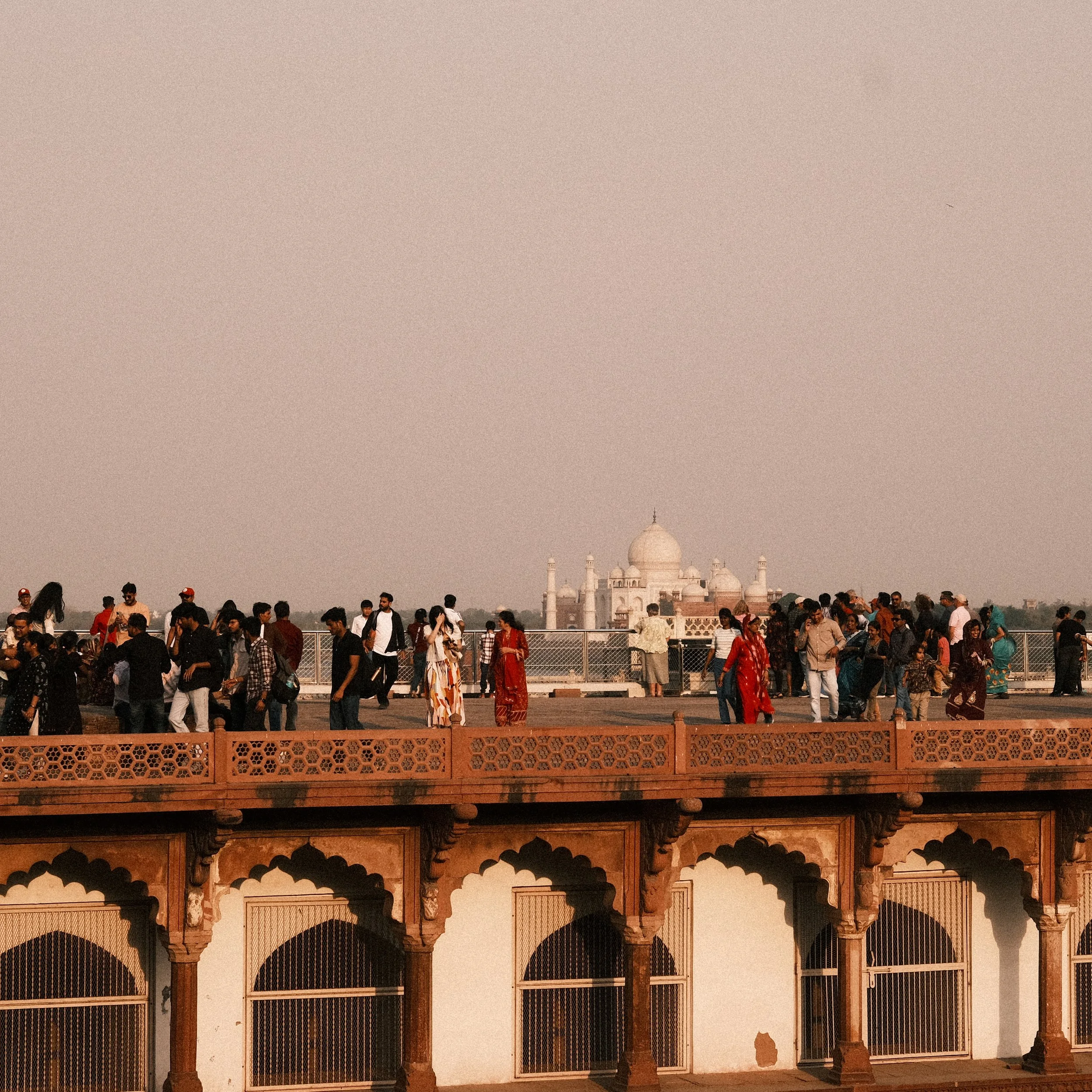 Personas caminando sobre el Fuerte de Agra con el Taj Mahal al fondo