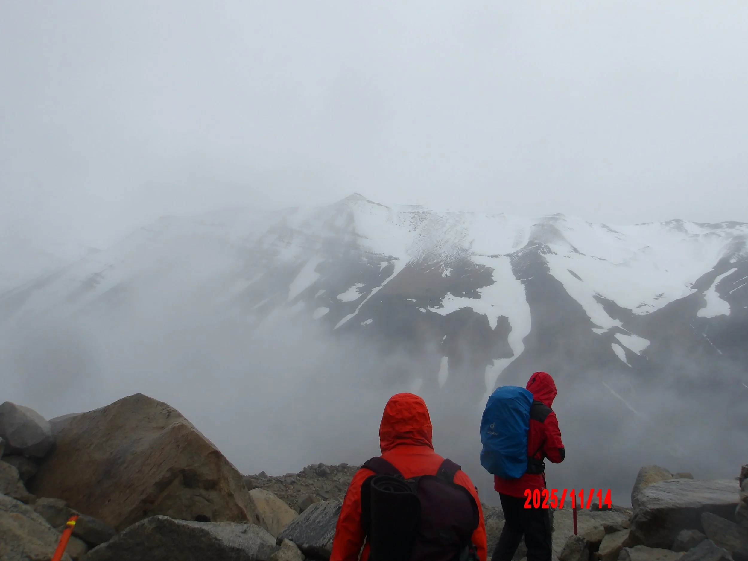 Paisaje nublado con dos personas, con montañas nevadas al fondo  en el W trek