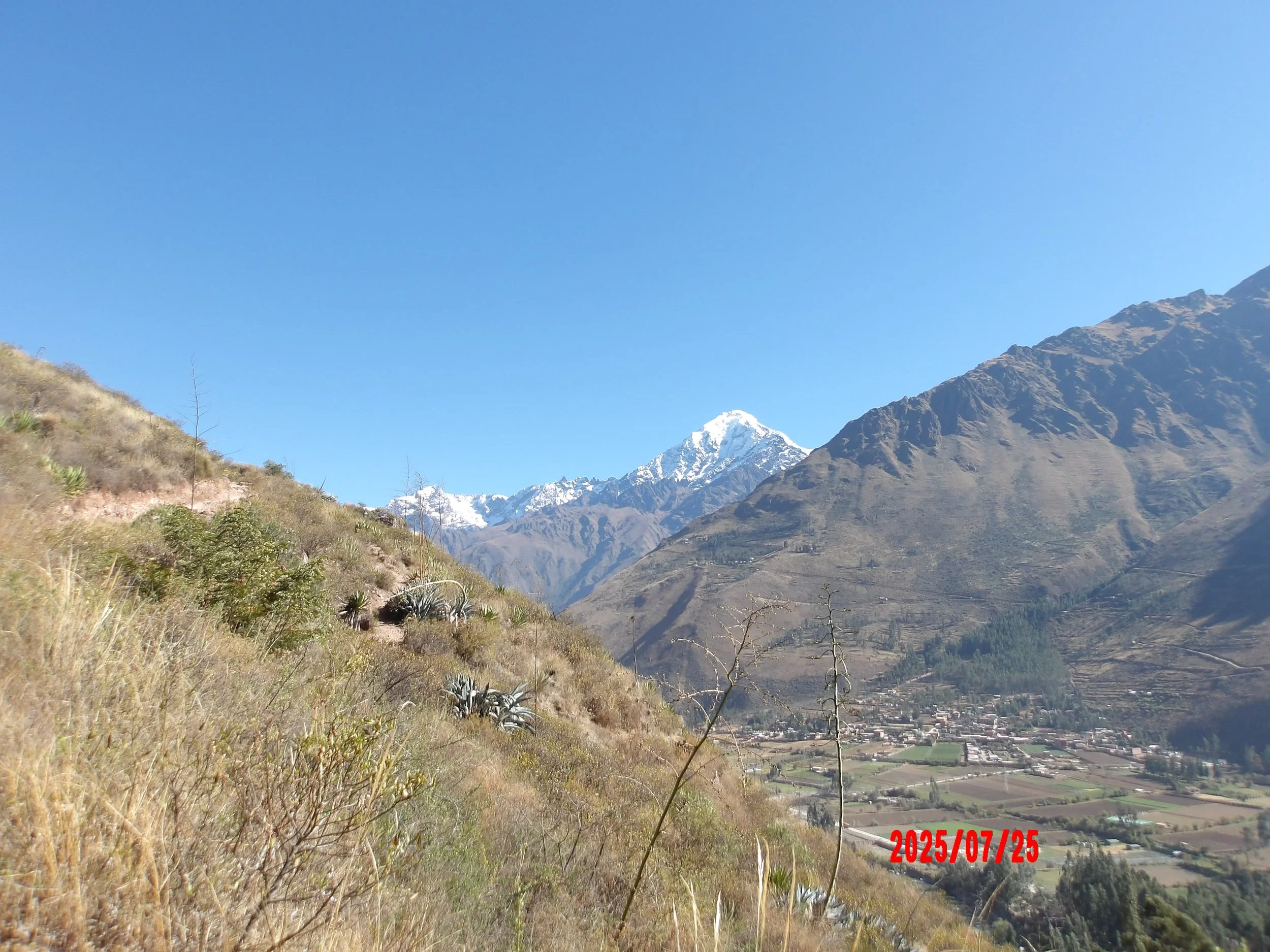 Sendero a las ruinas de Inti Punku con montañas nevadas al fondo.