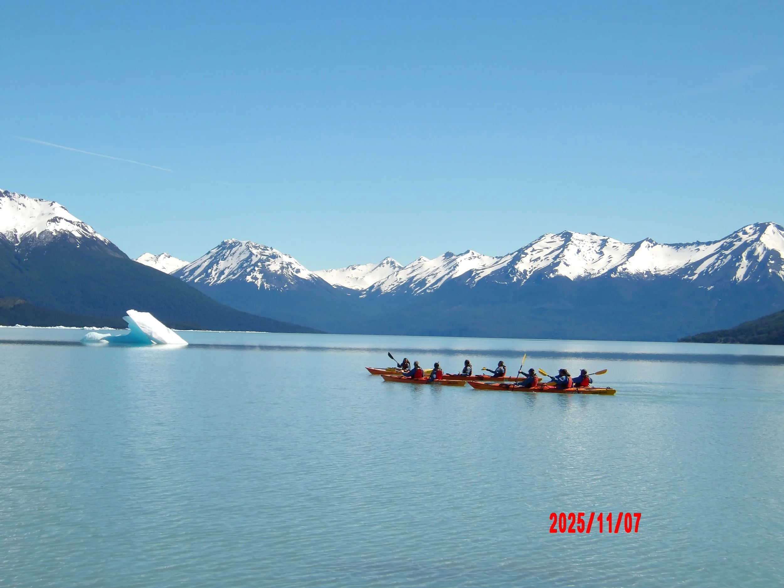 Personas en kayak en un lago con montañas nevadas al fondo, en Patagonia, Argentina.