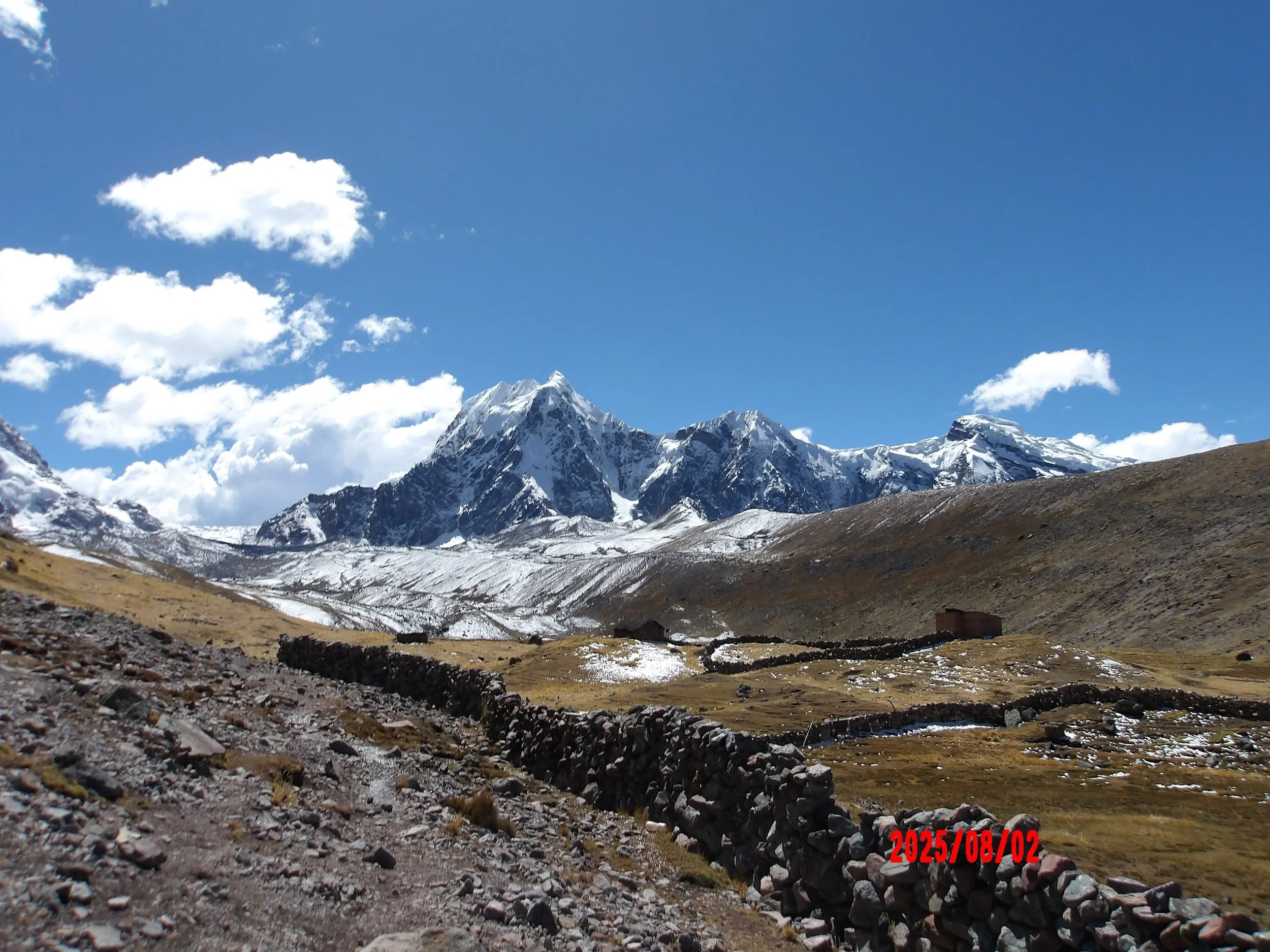 Trek de Ausangate con muro de piedras y montaña nevada al fondo