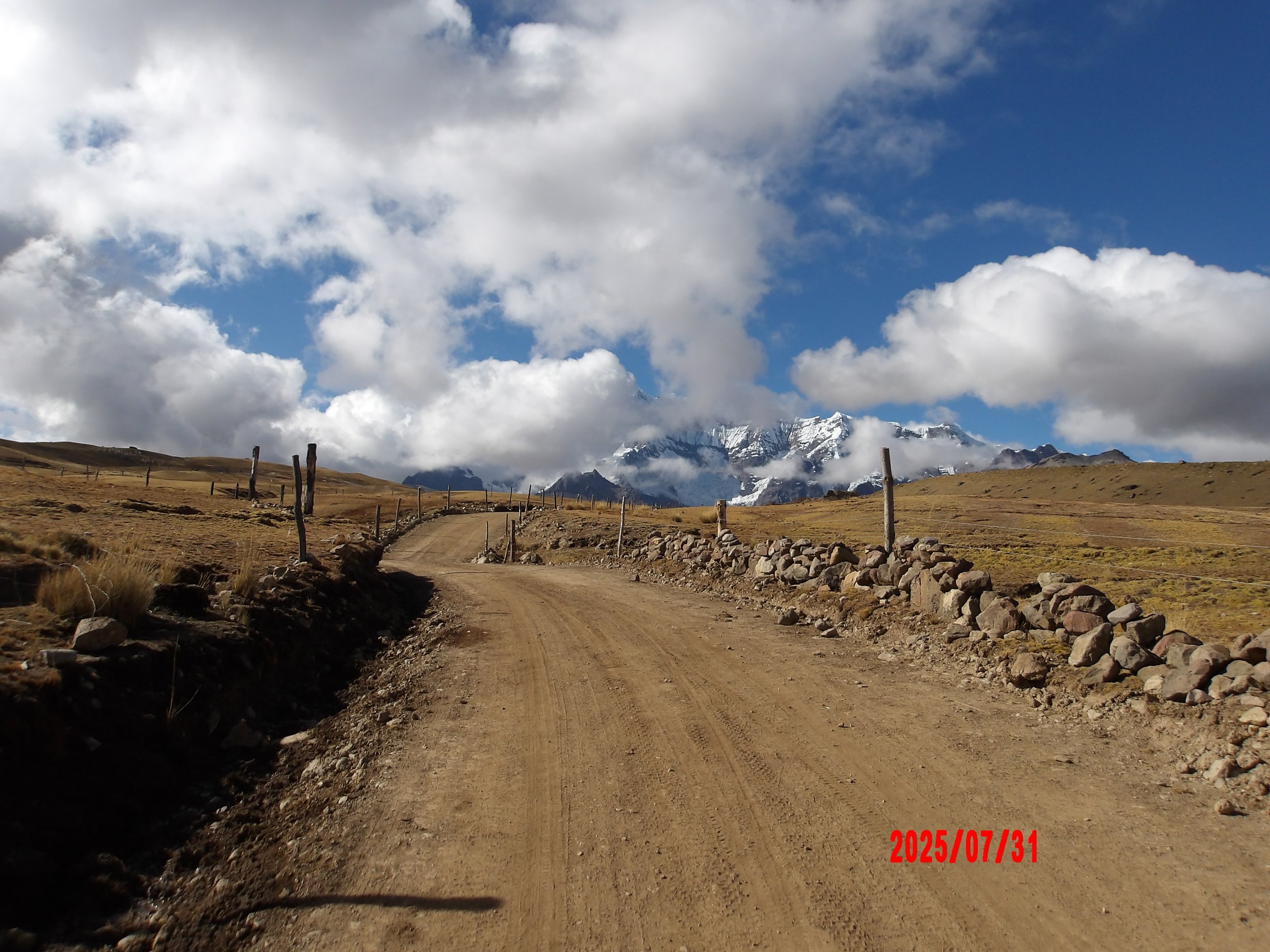 Camino de tierra con un pico nevado al fondo en Perú.