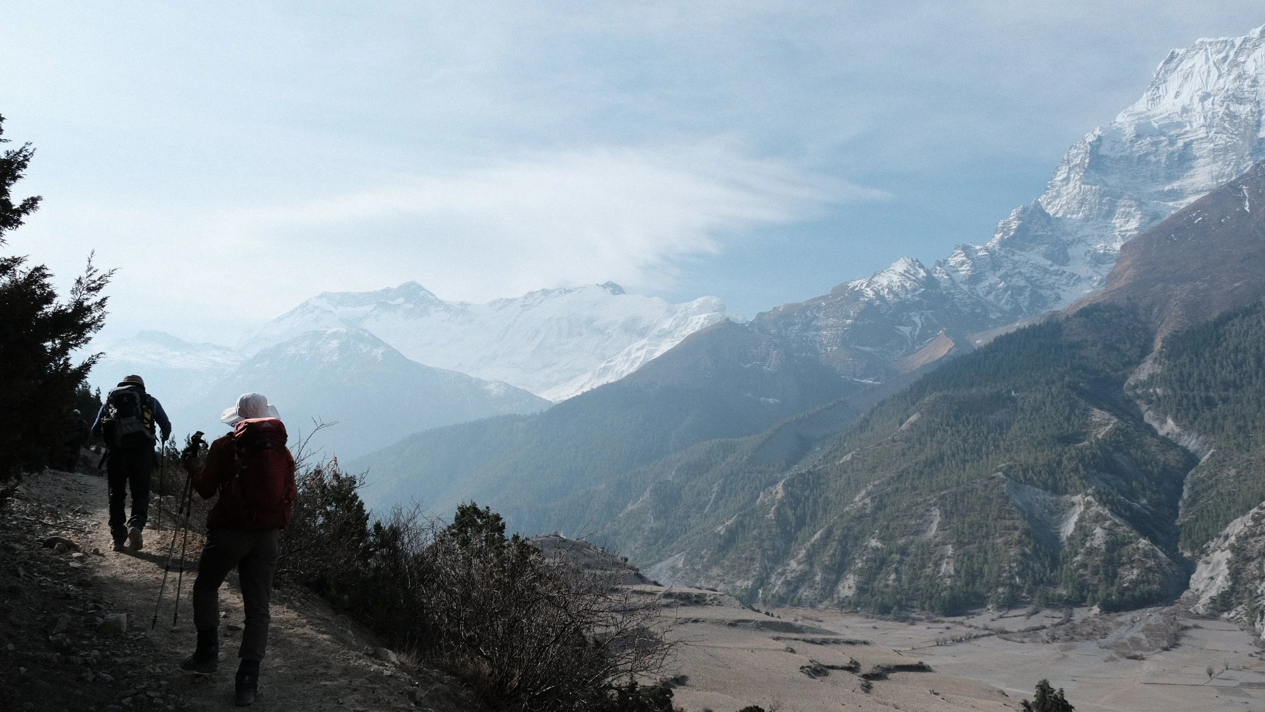 Personas caminando en Nepal con montañas nevadas al fondo.