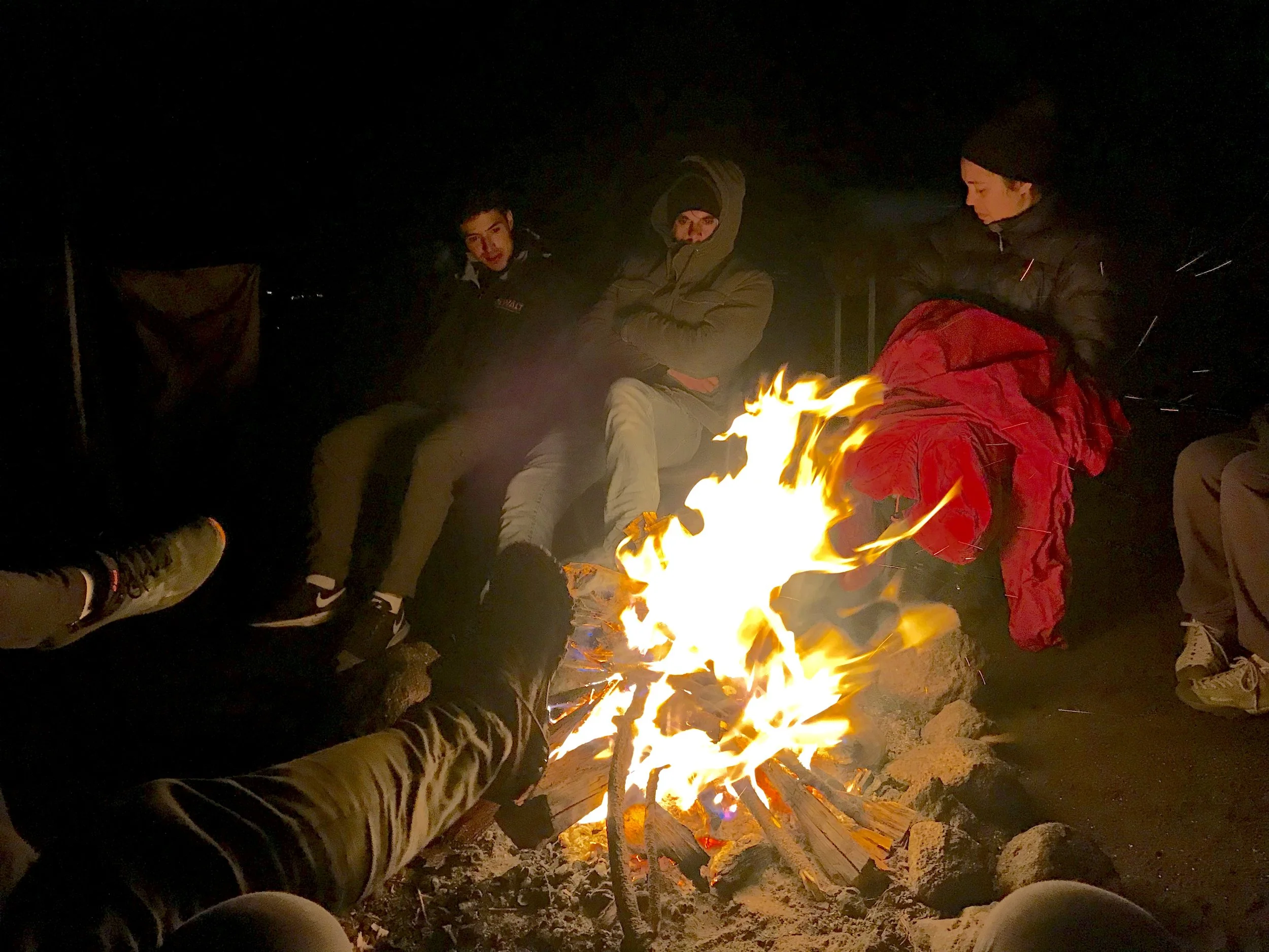 Personas descansando alrededor de una fogata.