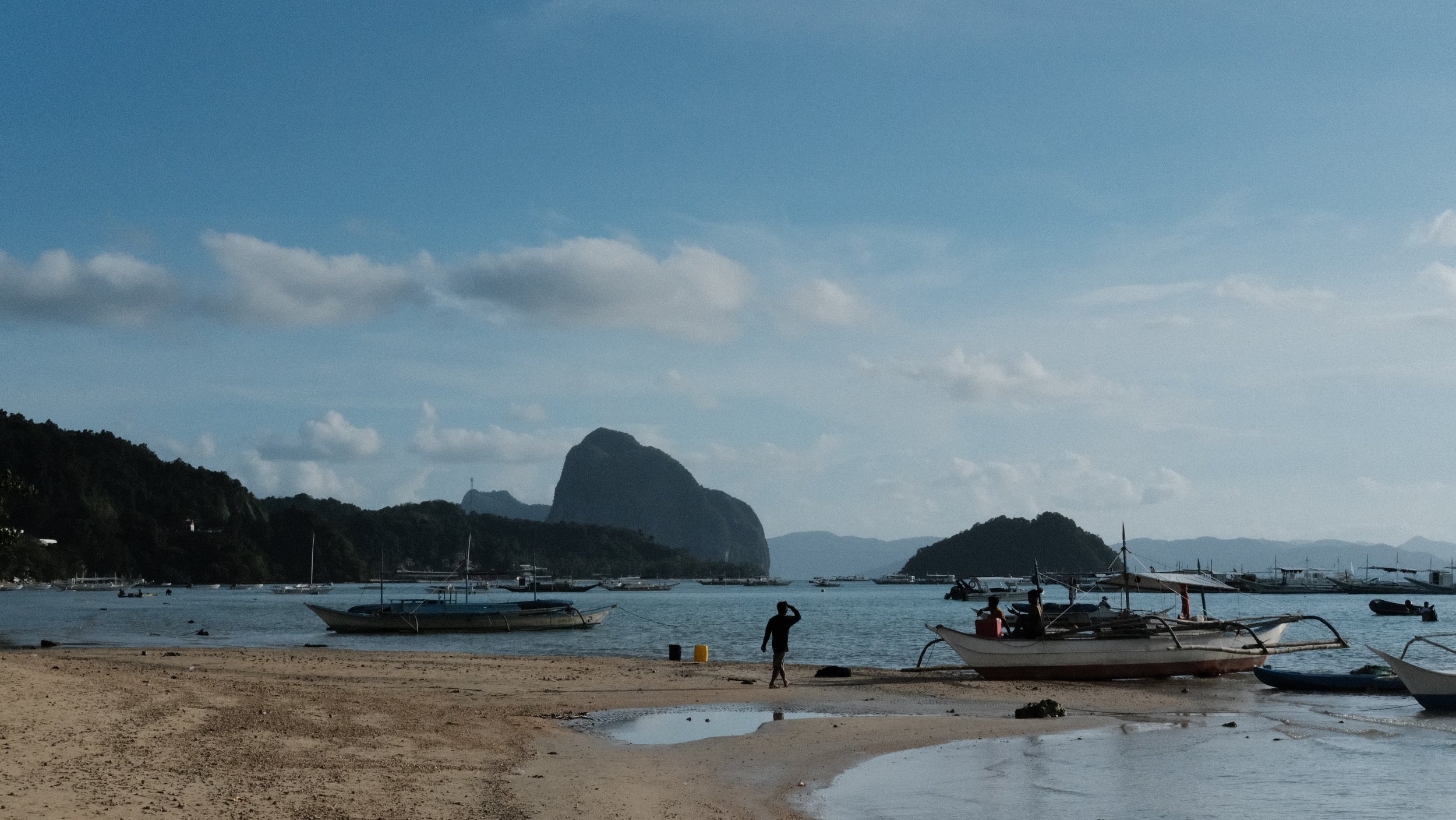 Persona caminando a un bote en una playa de El Nido