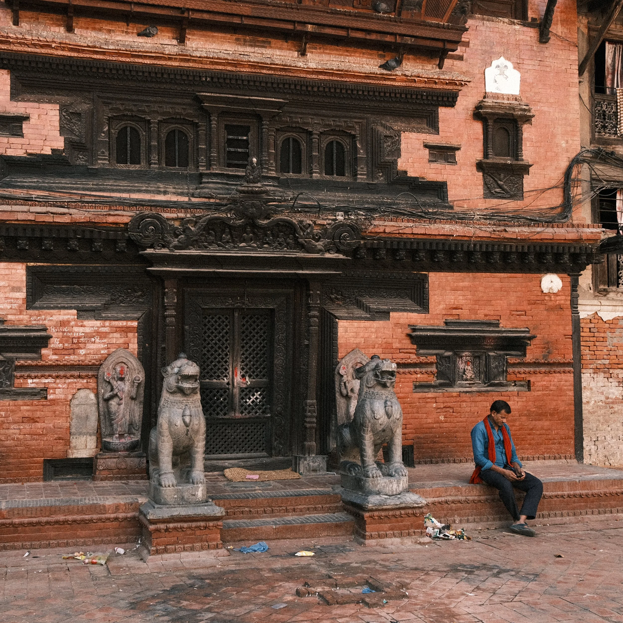 Hombre sentado en un edificio en la plaza Durbar