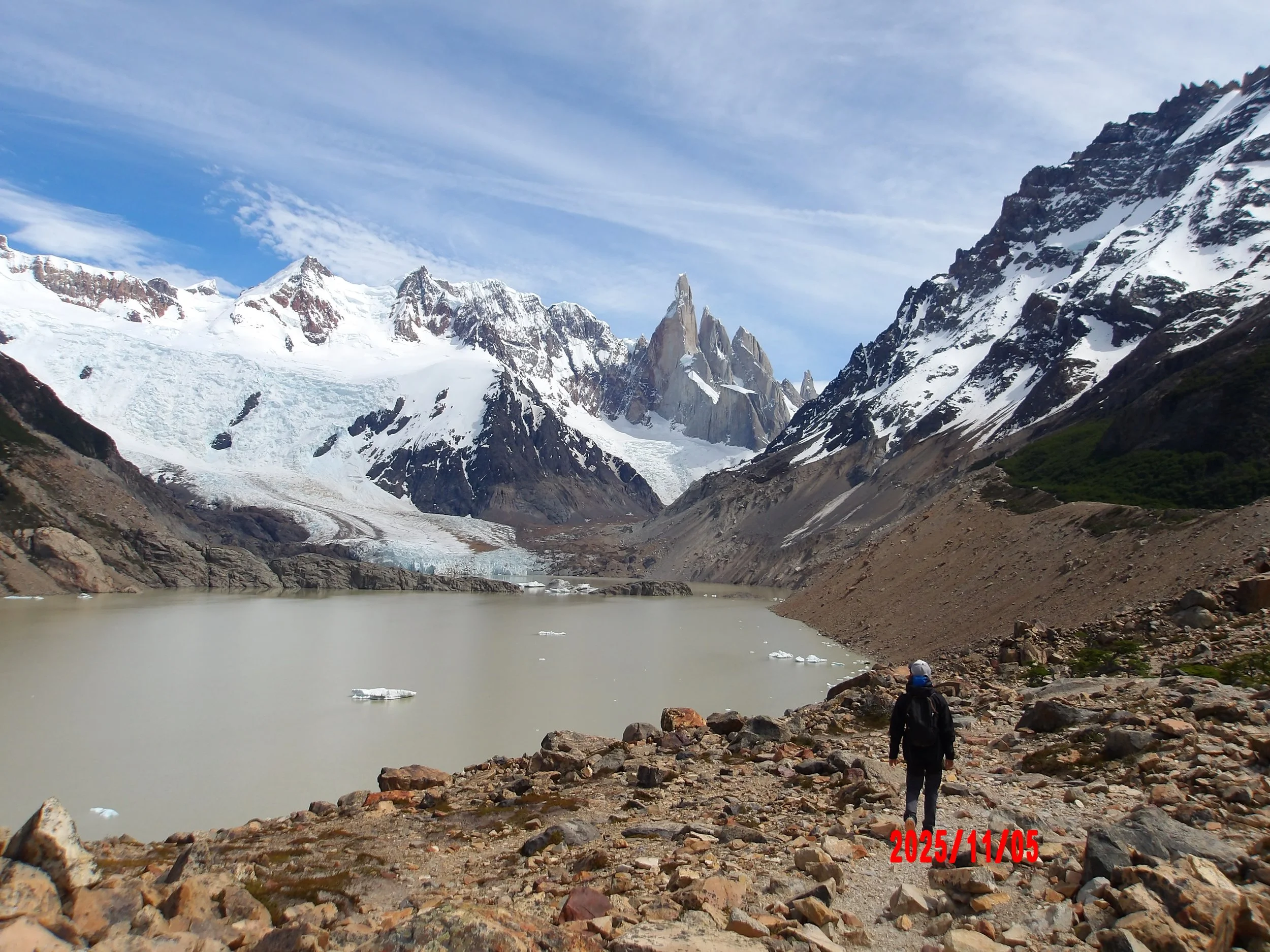 Persona caminando con la laguna Torre al lado y glaciar al fondo, en Patagonia, Argentina.