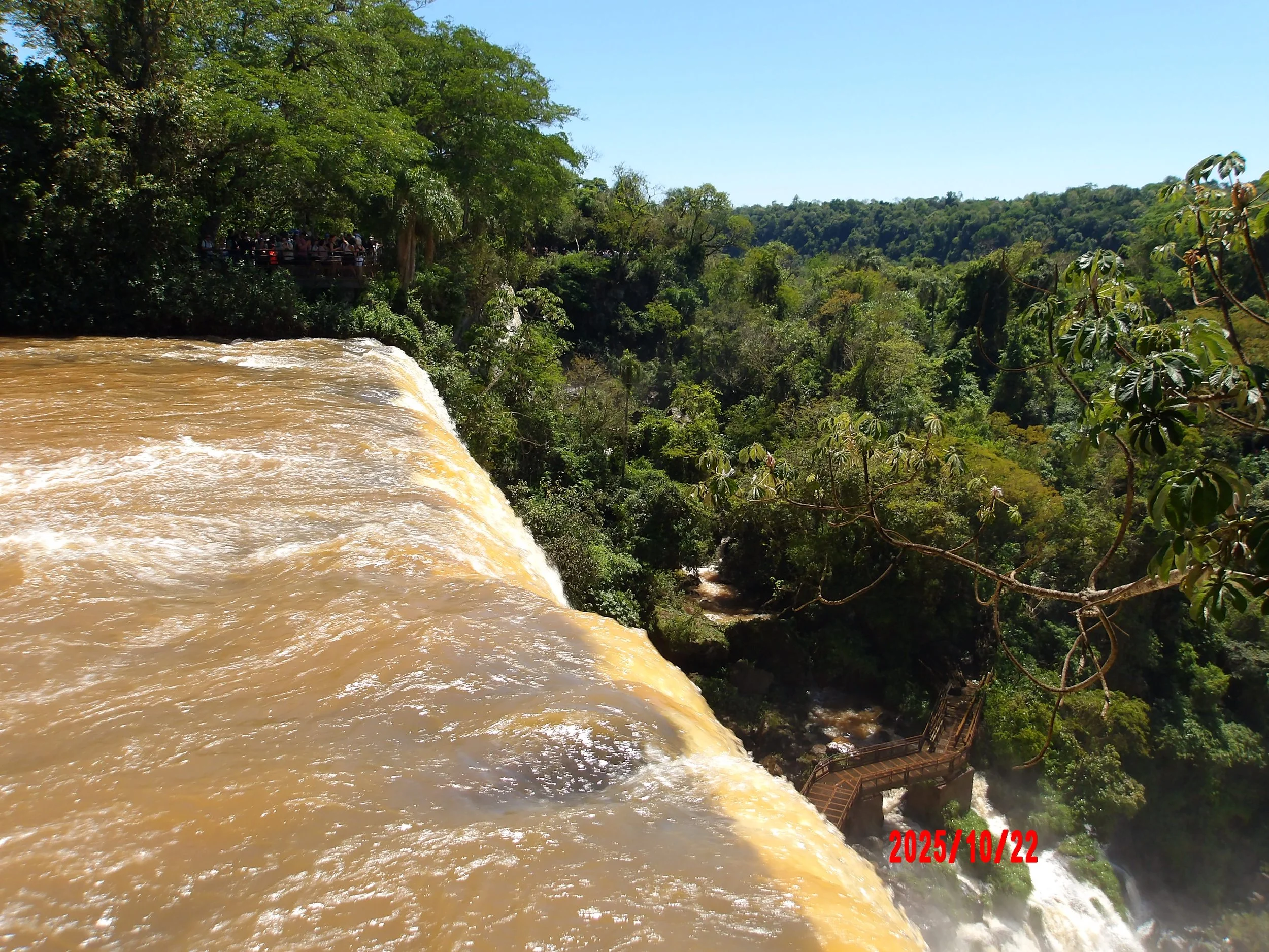 Cascada en las cataratas del Iguazú con una pasarela abajo en la esquina izquierda