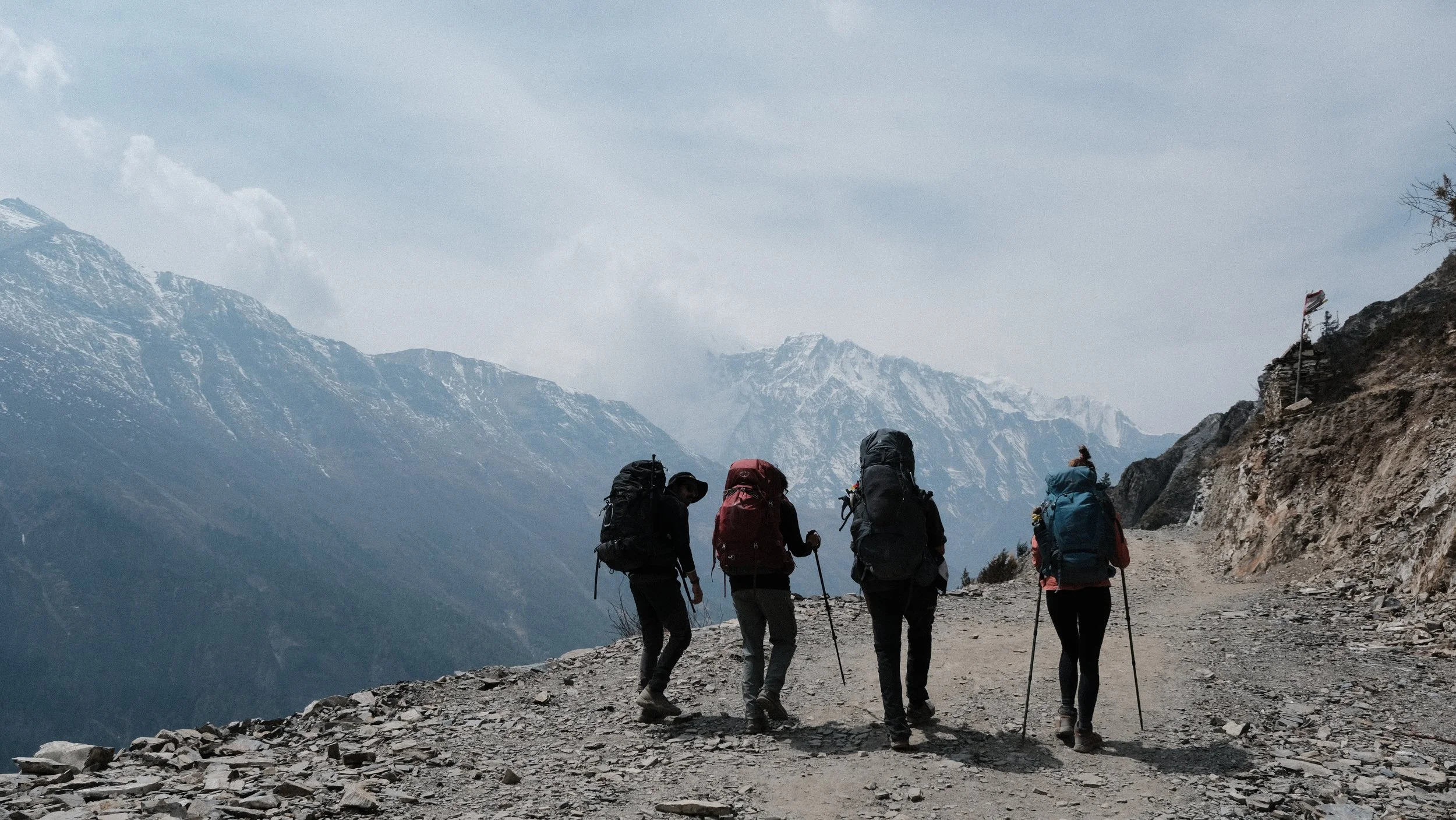 Personas caminando en Nepal con montañas nevadas en el fondo.