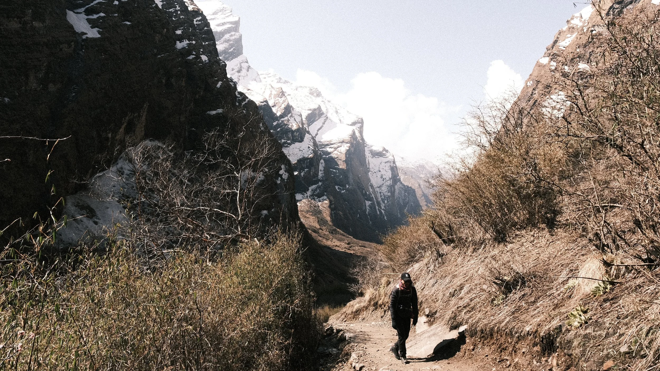 Persona caminando en el trek al campamento base de Annapurna con montañas al fondo