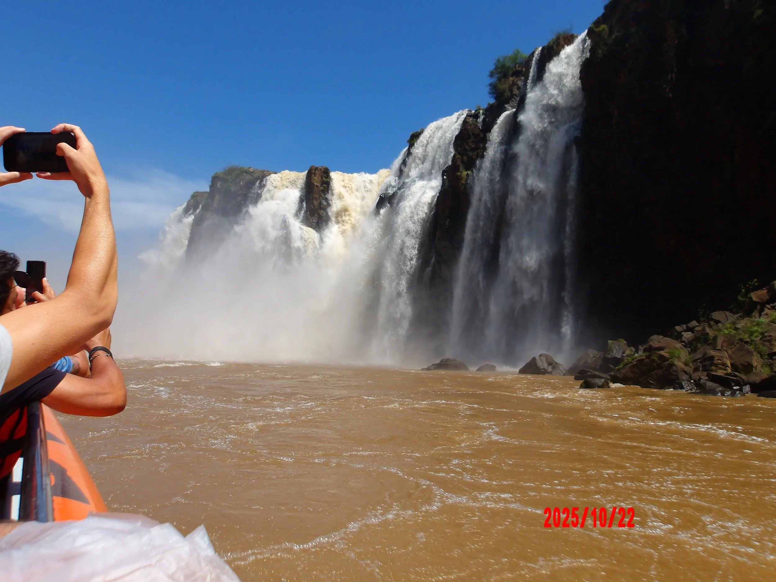Personas tomando fotos a las cataratas del Iguazú desde un bote