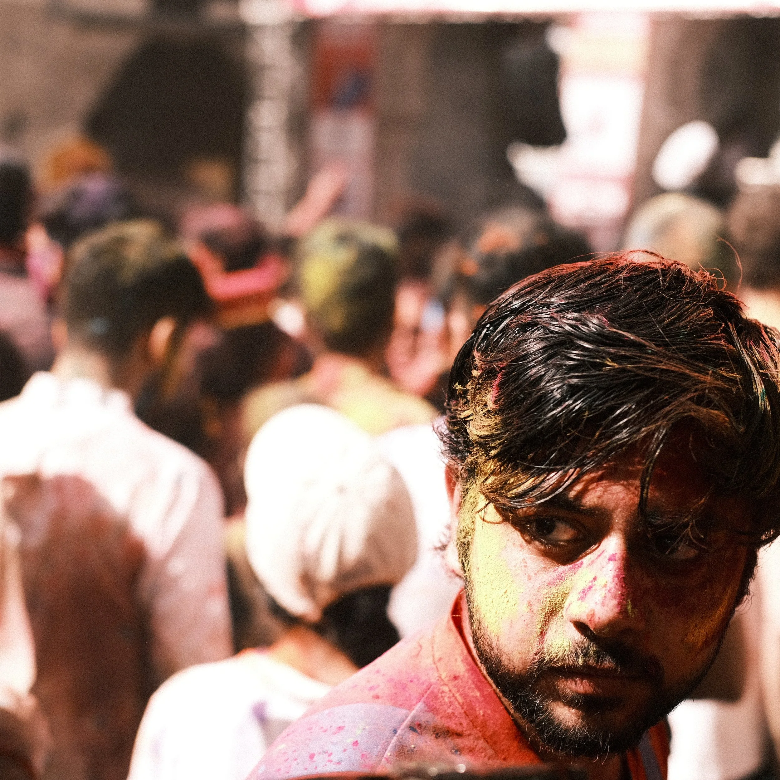 Hombre con mirada intensa lleno de color durante Holi en India