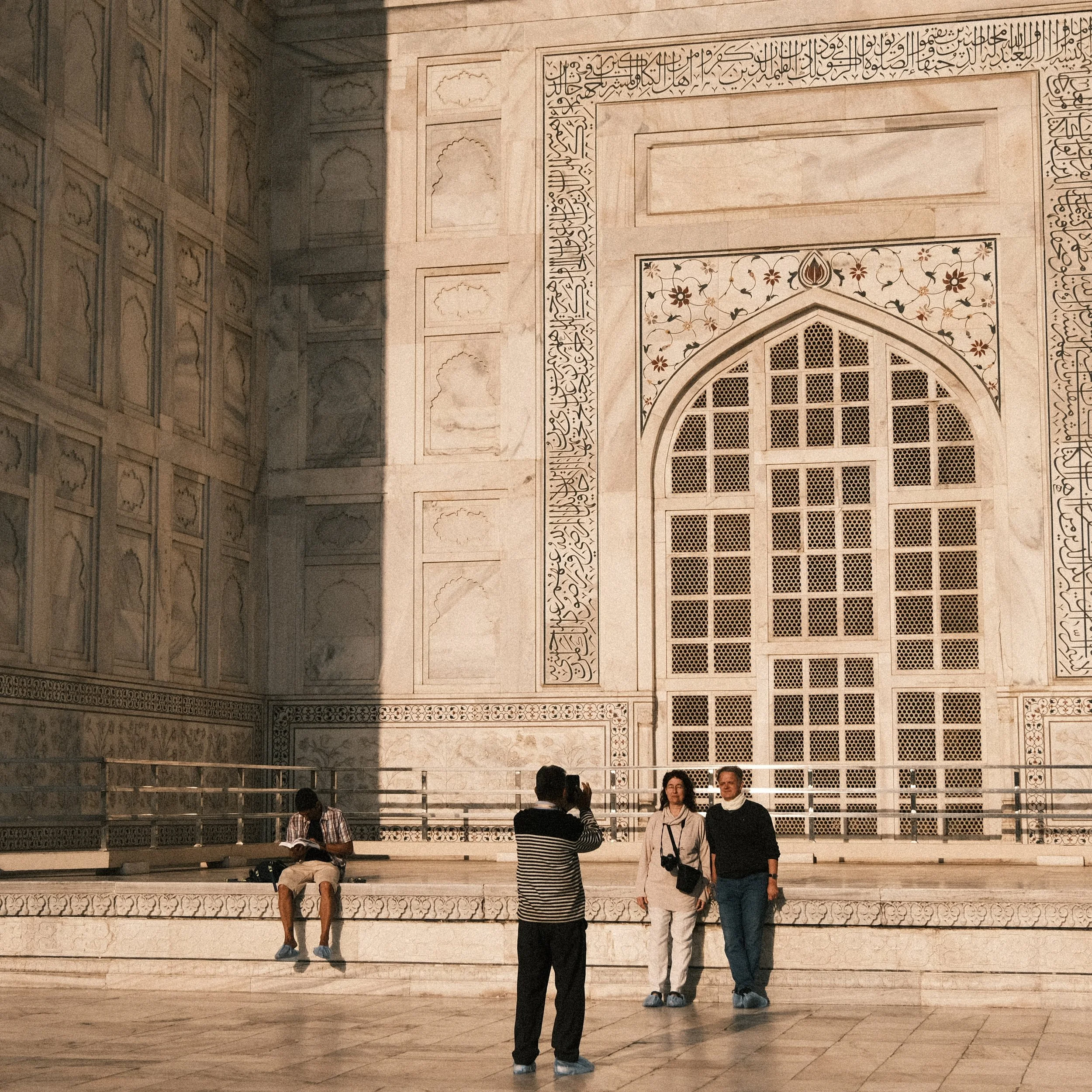 Pareja siendo fotografiada y hombre sentado leyendo en el Taj Mahal