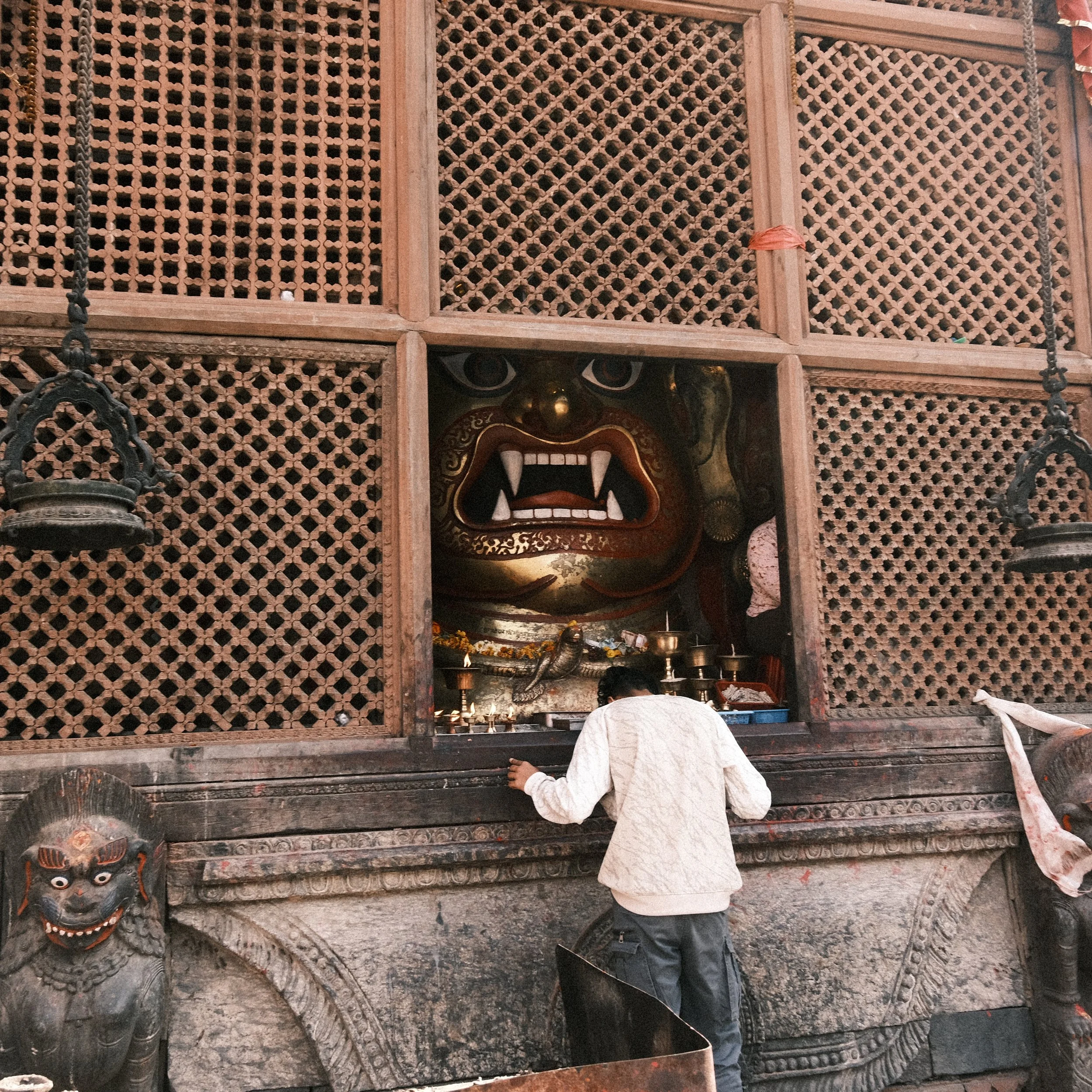 Hombre rezando frente a la cabeza de una deidad en la Plaza Durbar de Katmandú
