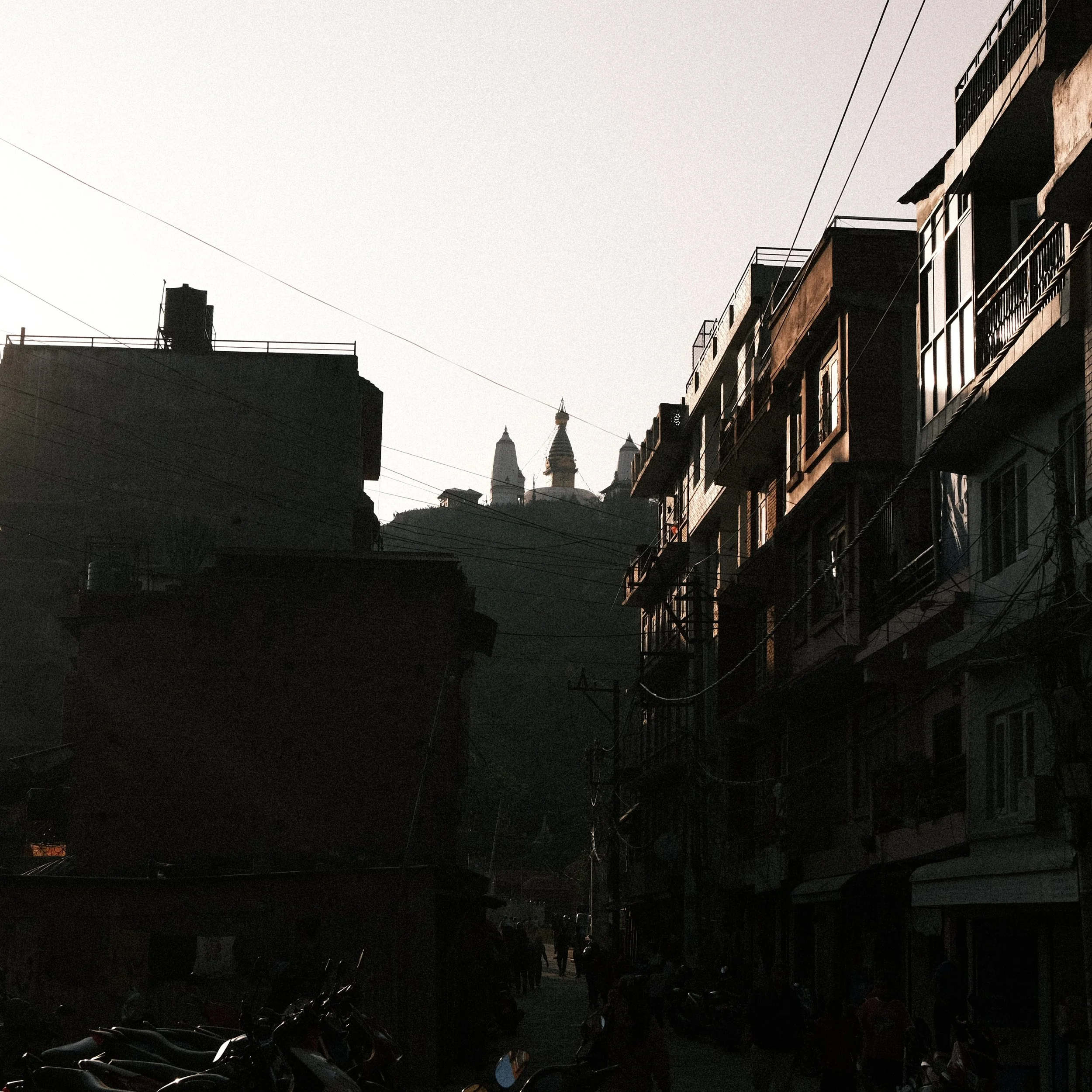 Calles de Katmandú oscuras con una estupa en la montaña al fondo