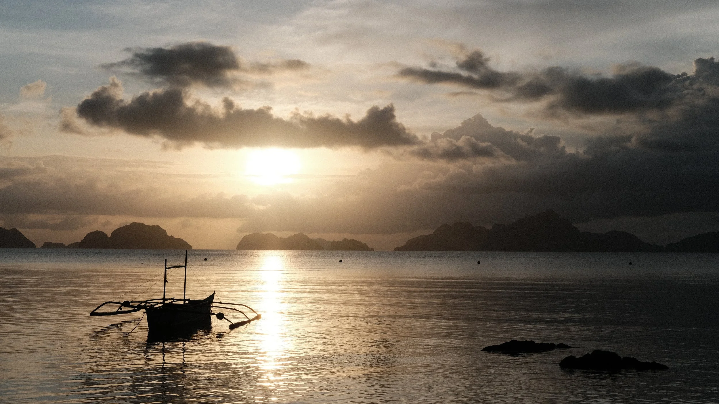 Anochecer desde una playa de El Nido con un bote