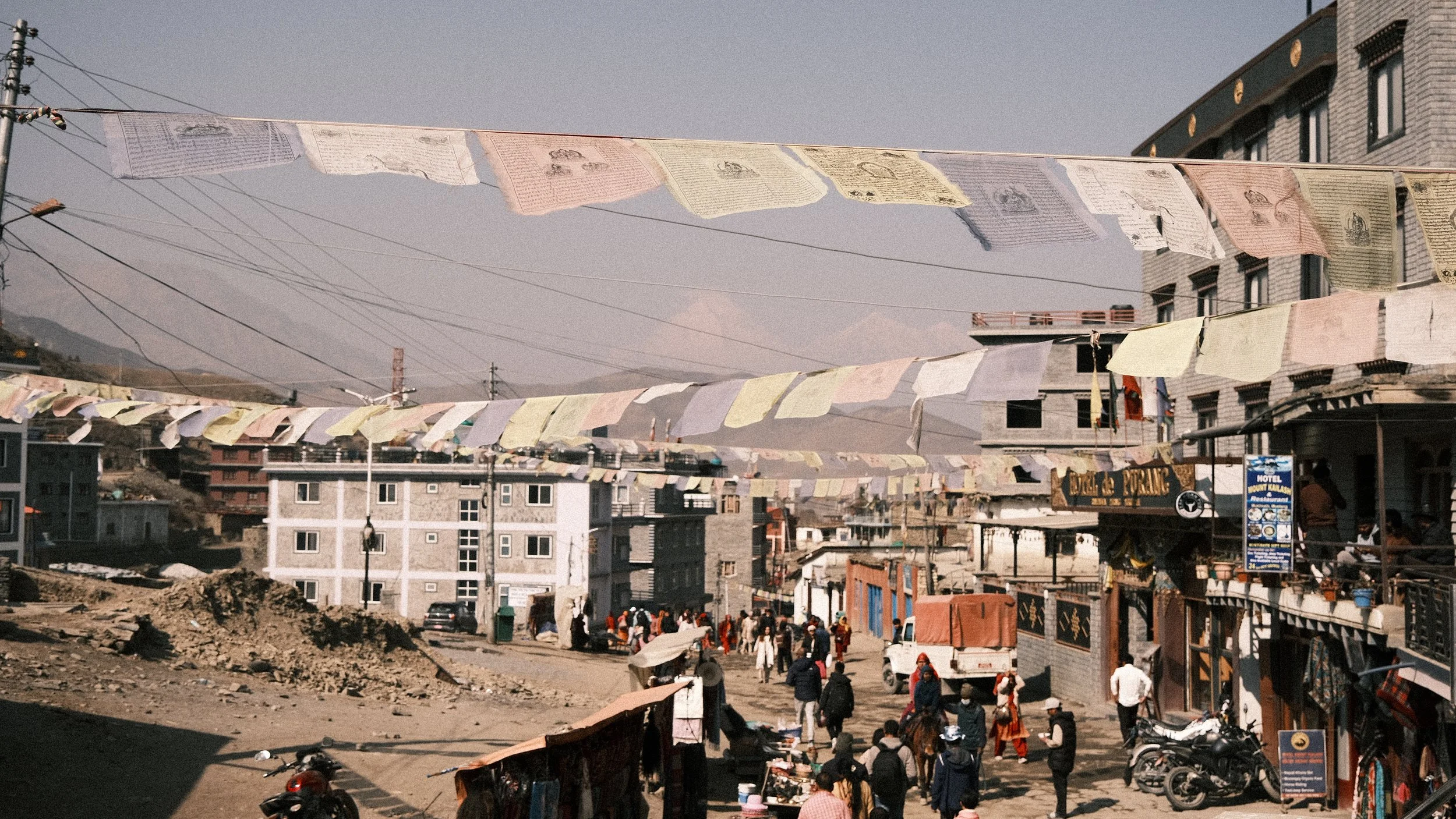 Pueblo con banderas de oración y montaña al fondo.