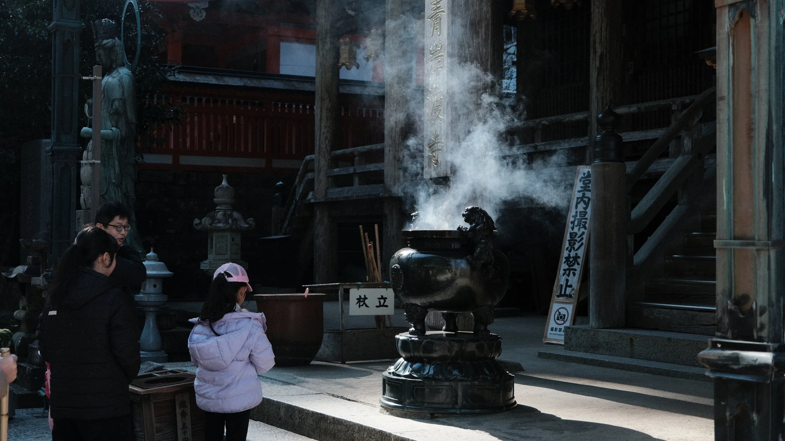 Personas en un templo japonés junto a caldero con humo.