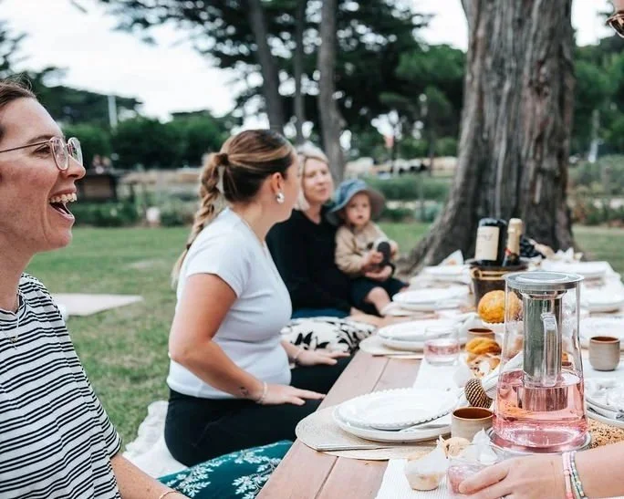 Guests enjoying a beautifully styled outdoor picnic experience, featuring elegant tableware, refreshments, and meaningful moments of connection in a natural setting.