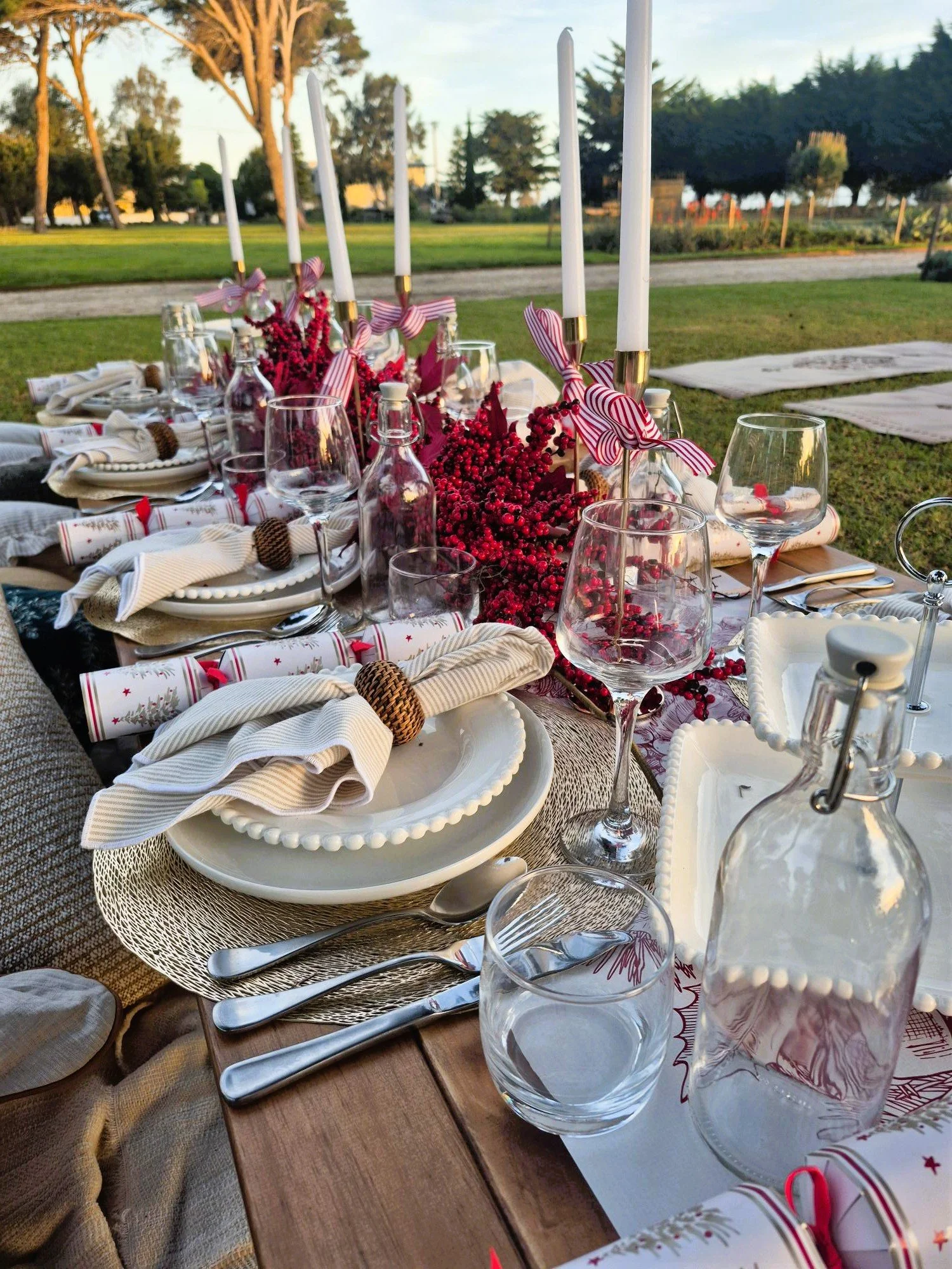 Elegant outdoor picnic setting featuring premium tableware, seasonal floral styling, linen napkins, and beautifully considered details in a scenic park location.
