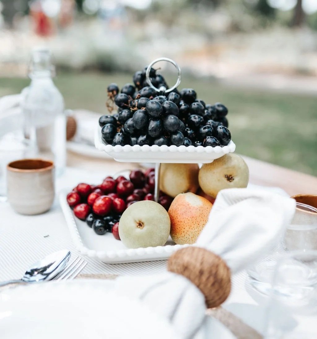 Luxury picnic setup in Melbourne featuring fresh seasonal fruit, elegant tableware, and refined outdoor styling.