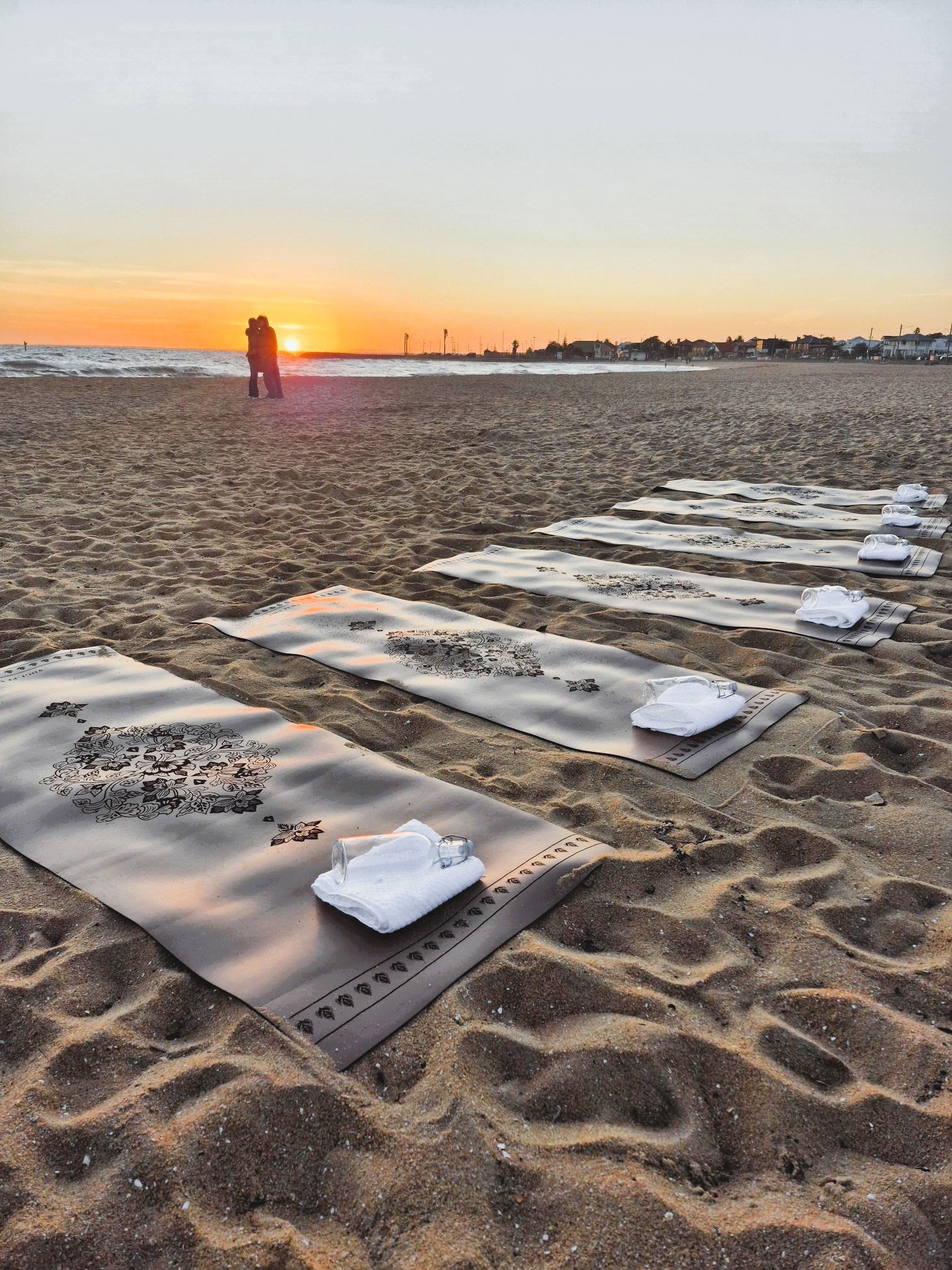 Sunset Pilates experience on a Melbourne beach with premium mats, towels, and a scenic coastal backdrop.