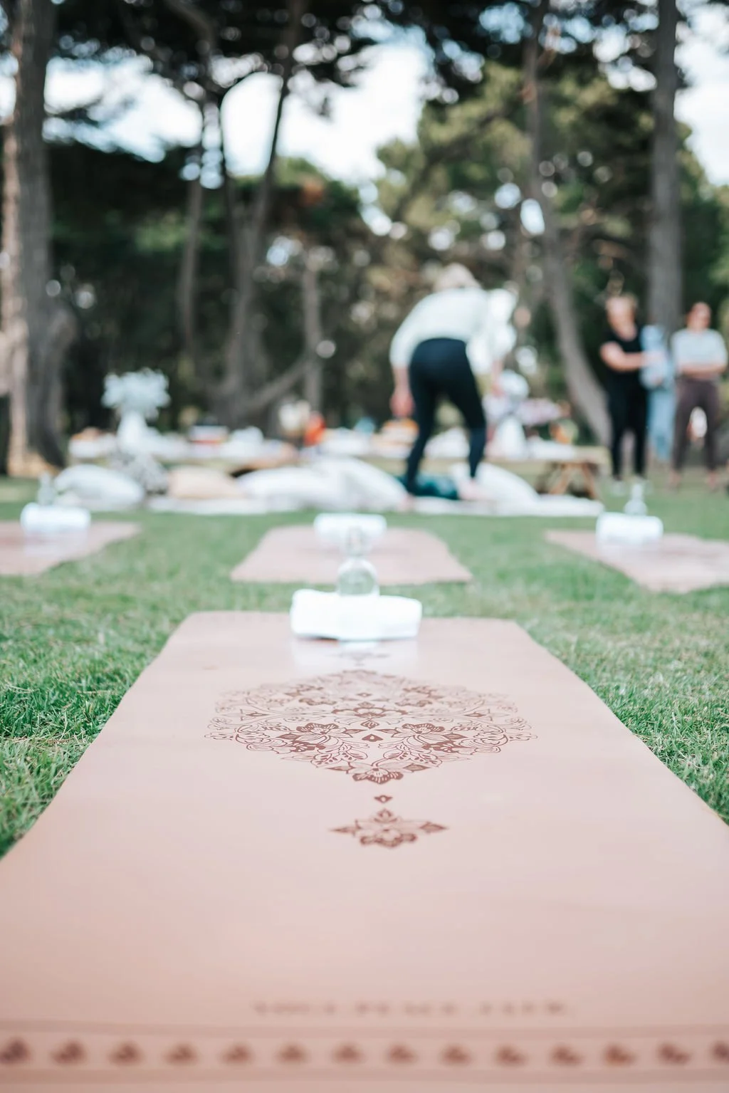 Premium Pilates mats and elegant glassware arranged for a Pilates Picnic Melbourne experience, set within a scenic outdoor location surrounded by nature.